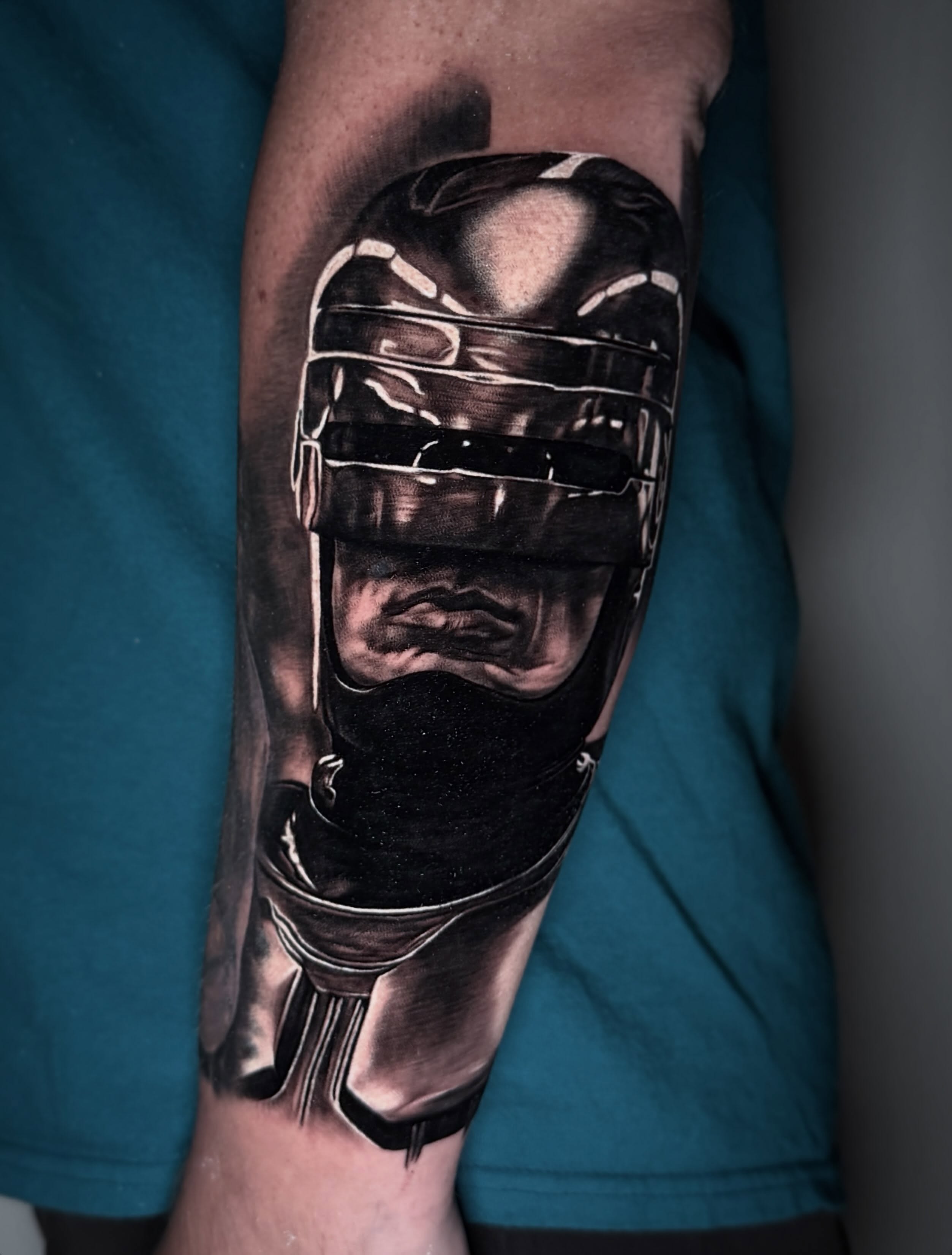 Robotic mask realism tattoo on the forearm by TJ Schunemann