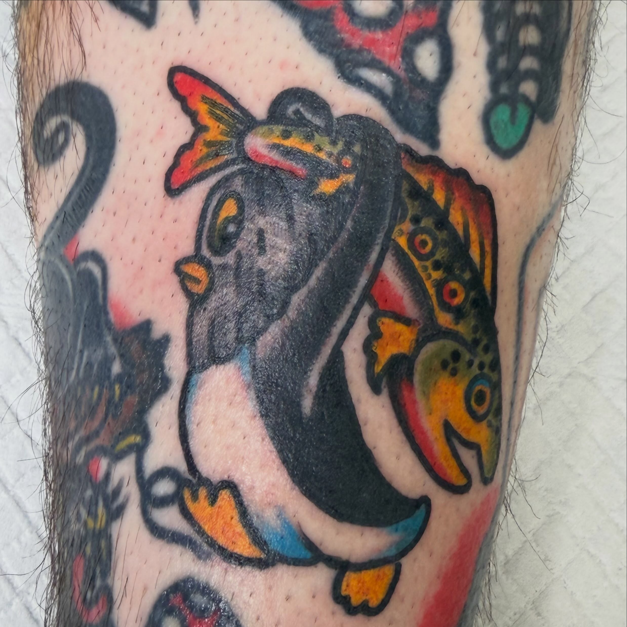 Penguin and fish American traditional tattoo on the forearm by dave rash
