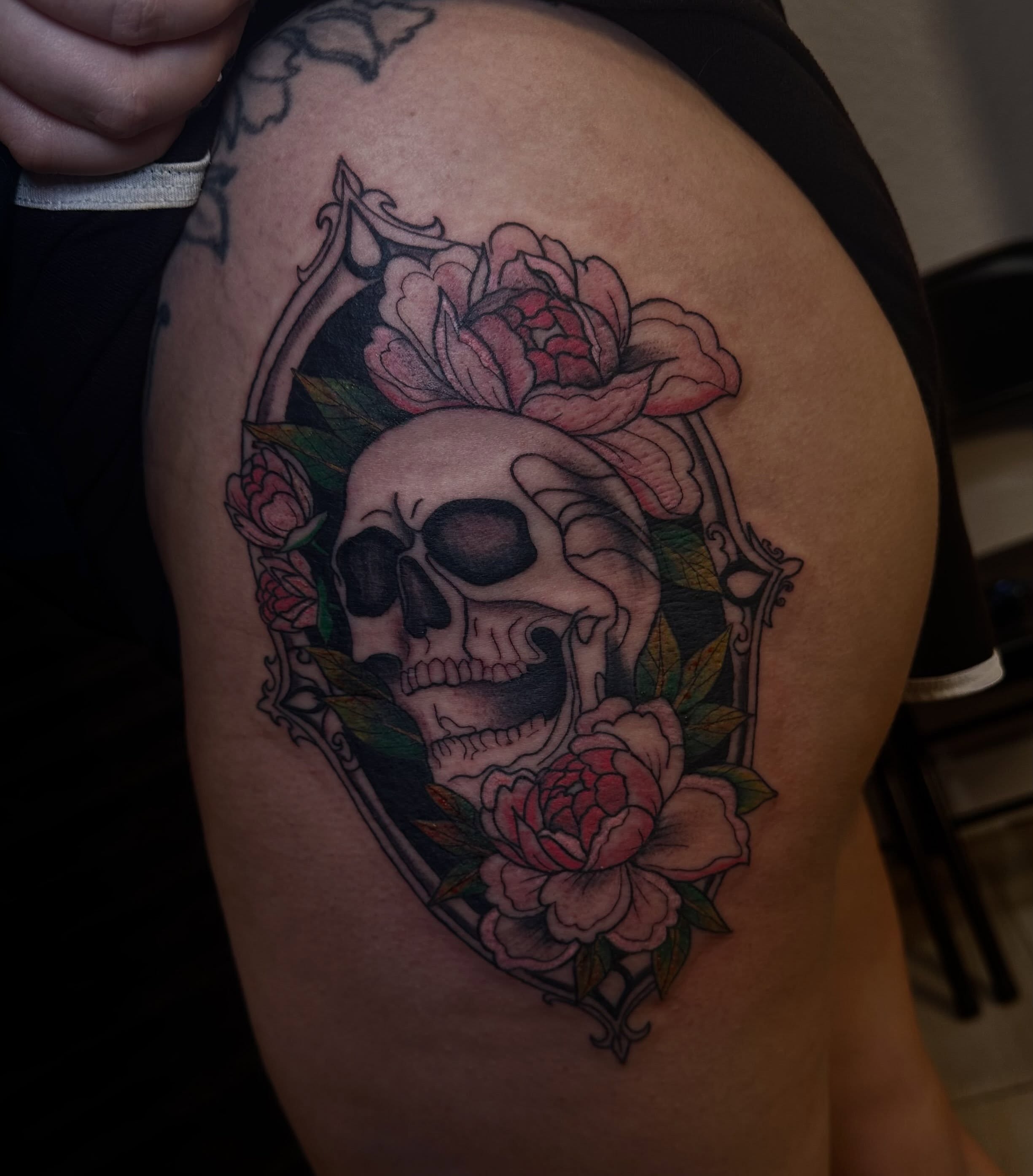 Skull and roses American traditional tattoo on the thigh by Marly Quinn