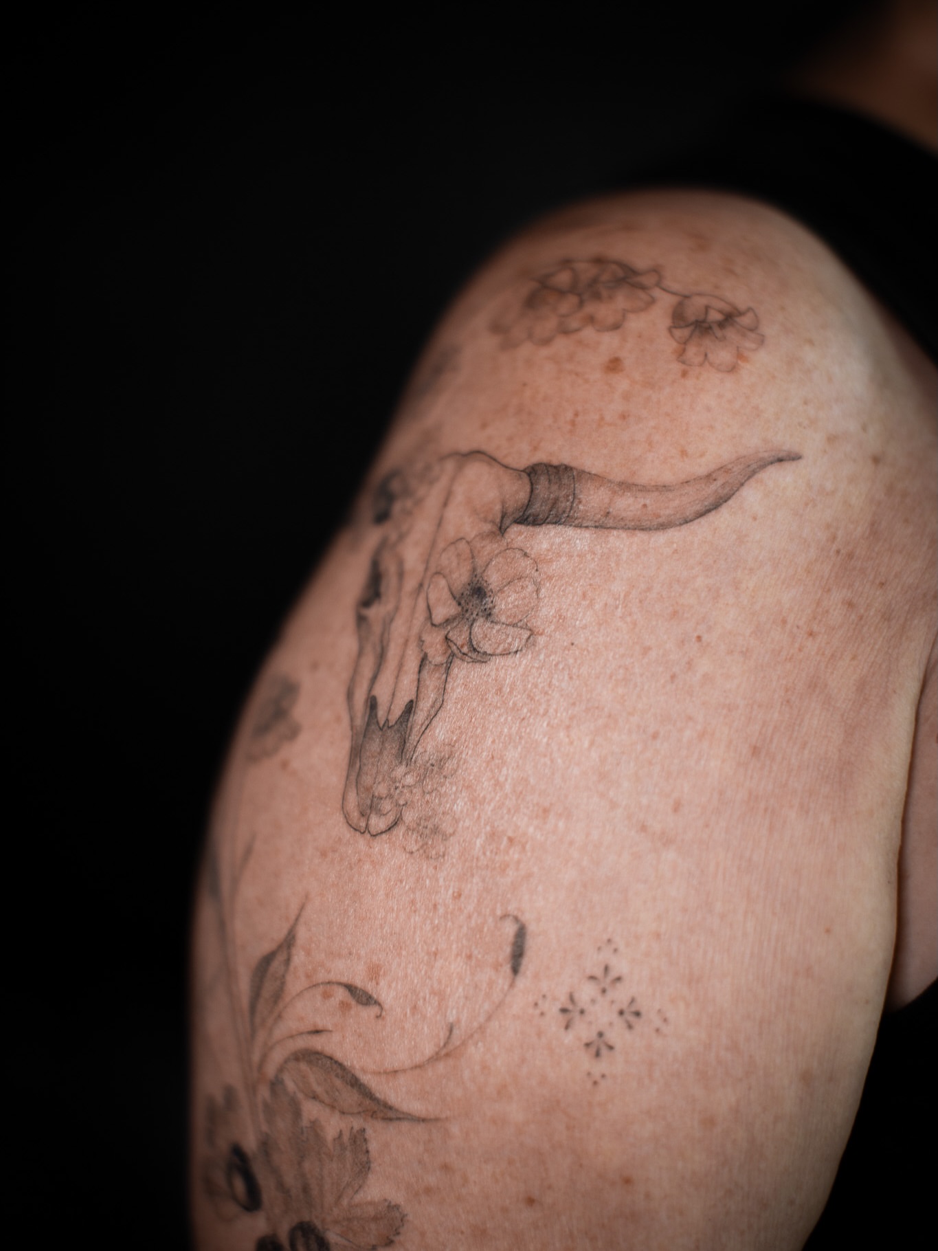 Bull skull with flowers black and grey tattoo on the shoulder by Aries Rising