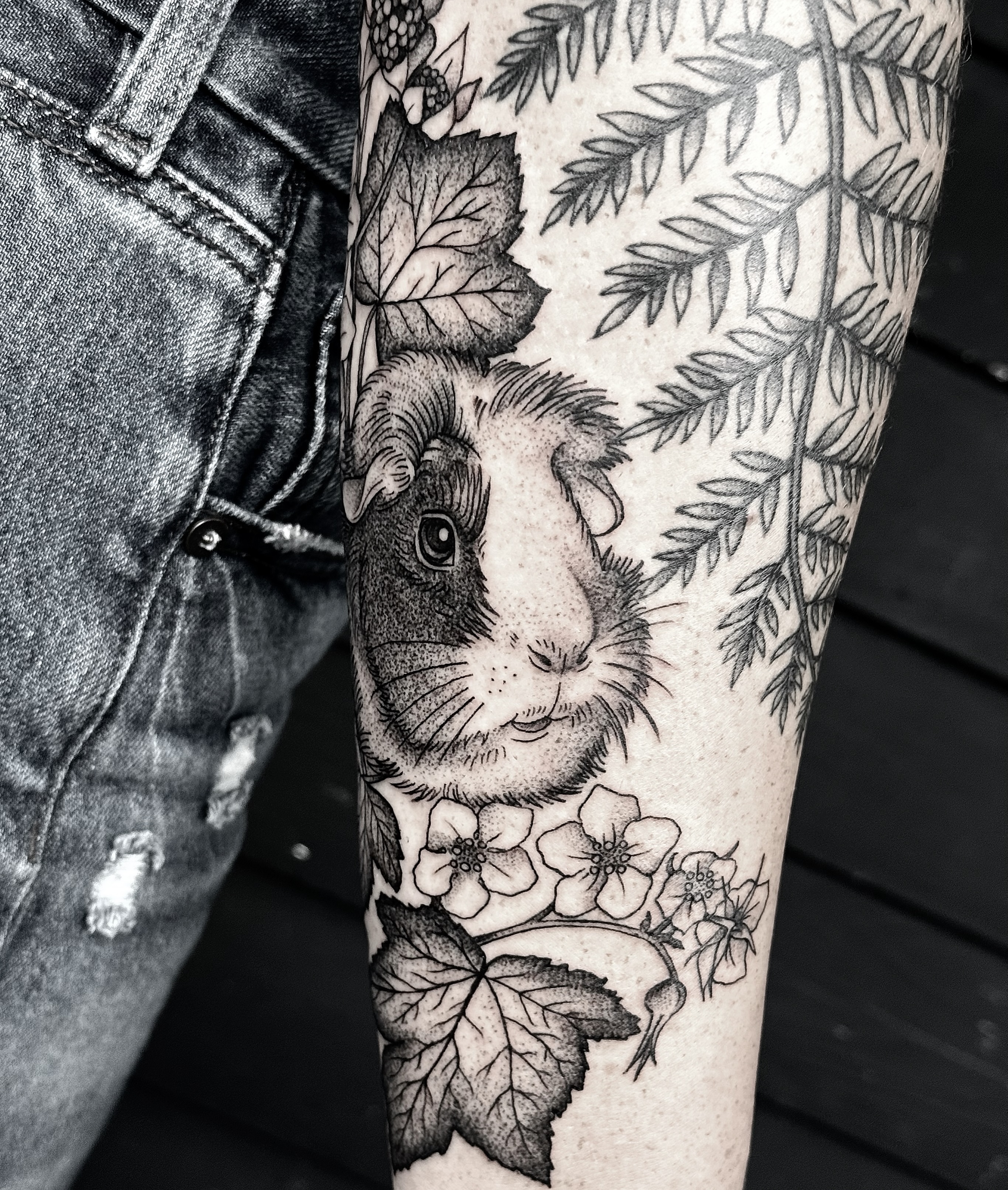 Guinea pig and flowers realism tattoo on the forearm by Breezy Tucker