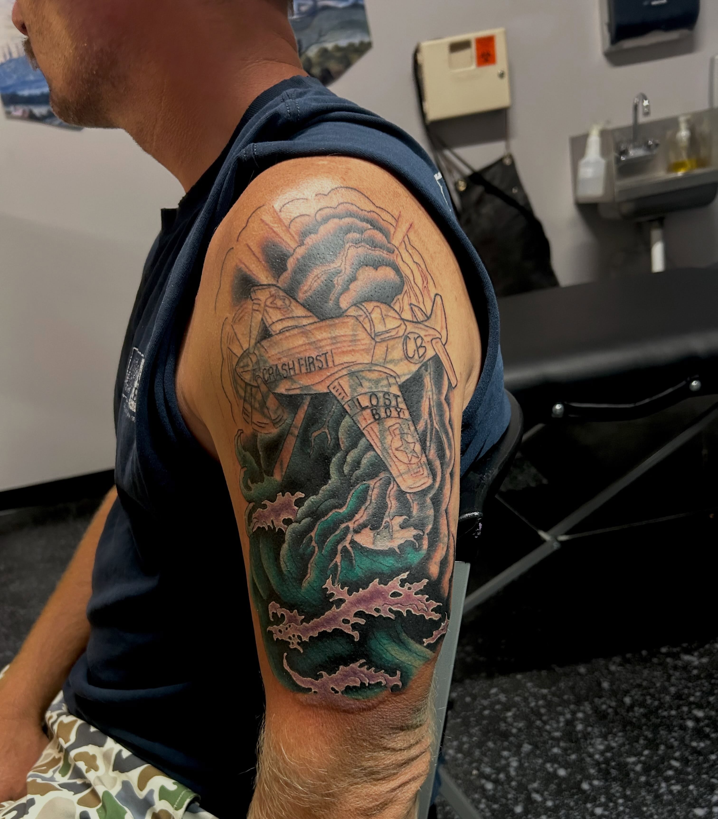 Airplane crash scene realism tattoo on the upper arm by Jamie Winn