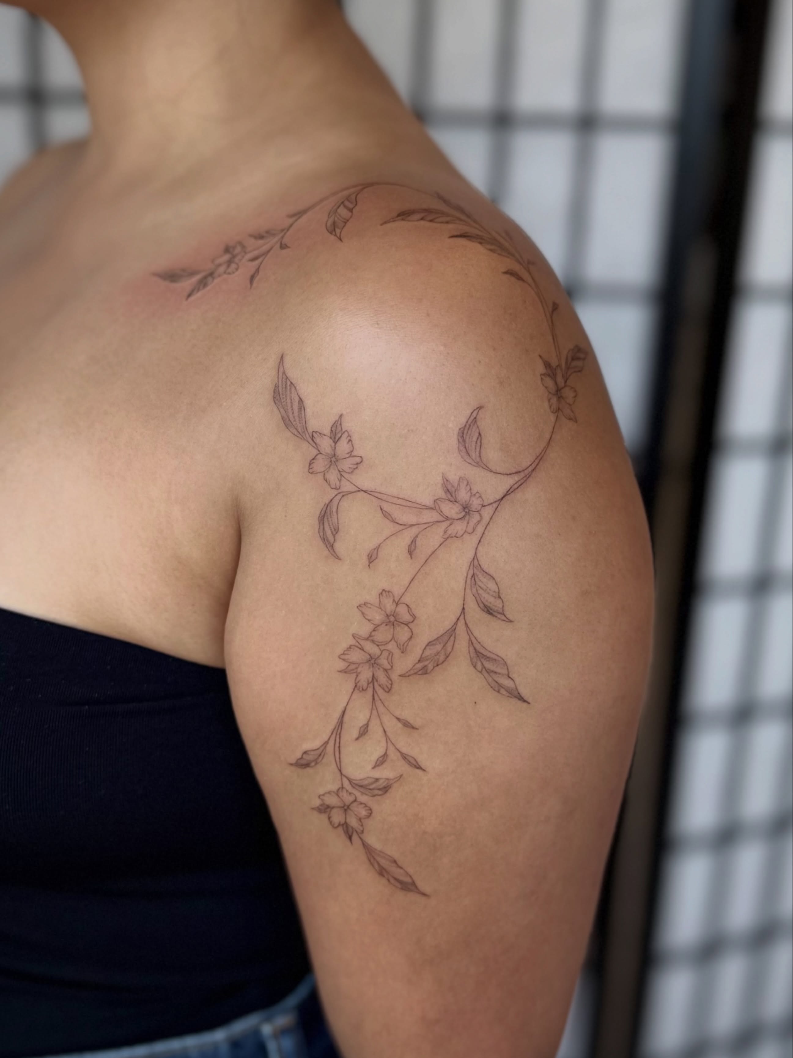 Floral vine fine line tattoo on the shoulder by Jennifer Fuster