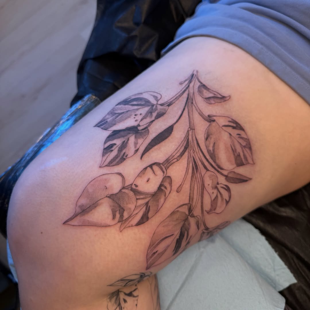Branch with leaves black and grey tattoo on the thigh by Kait