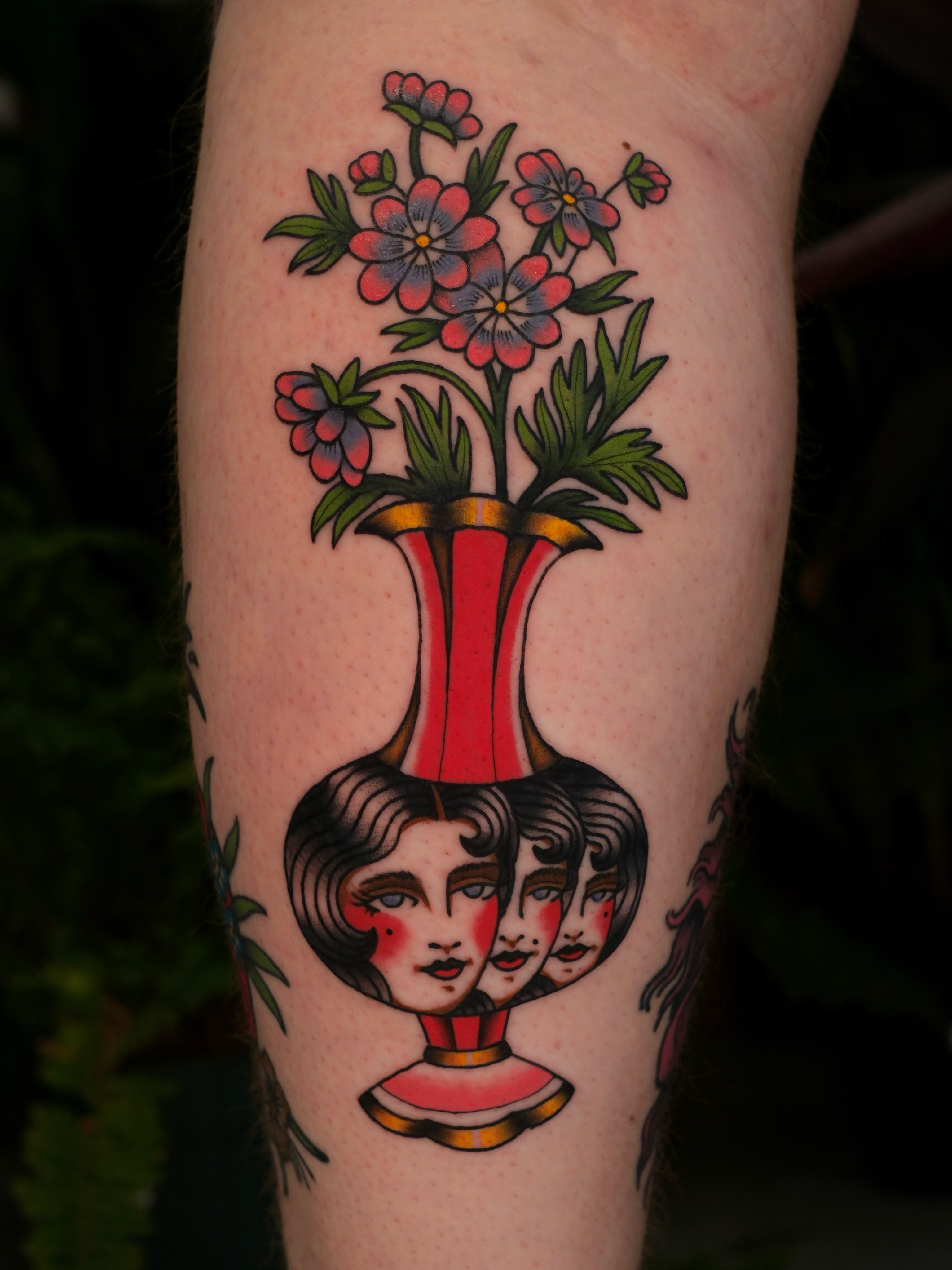 Floral arrangement with faces American traditional tattoo on the forearm by Mallory Murphy, Denton, Texas