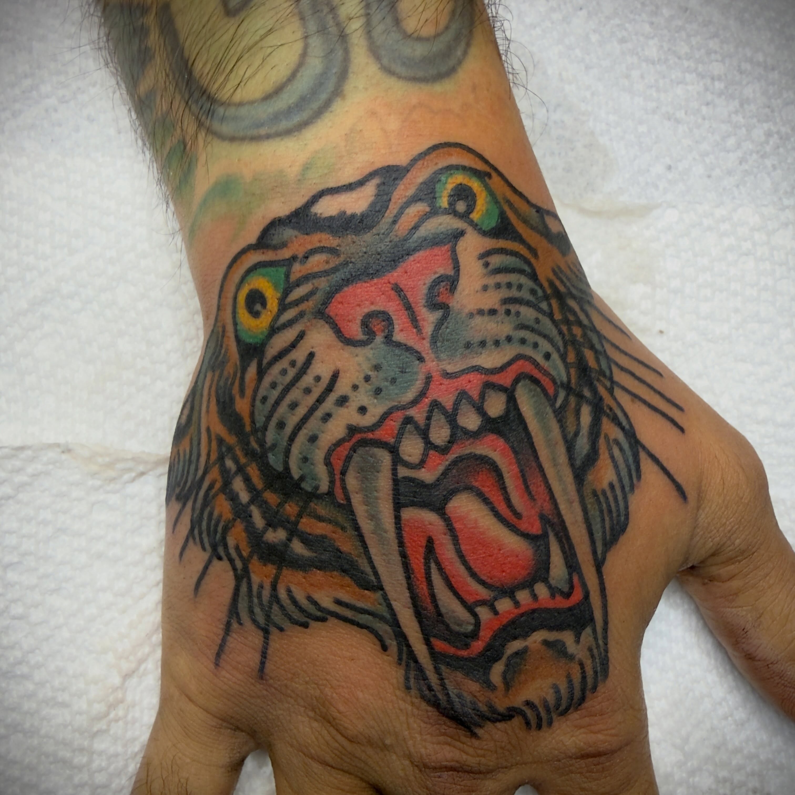 Roaring tiger American traditional tattoo on the hand by Andrew Slater