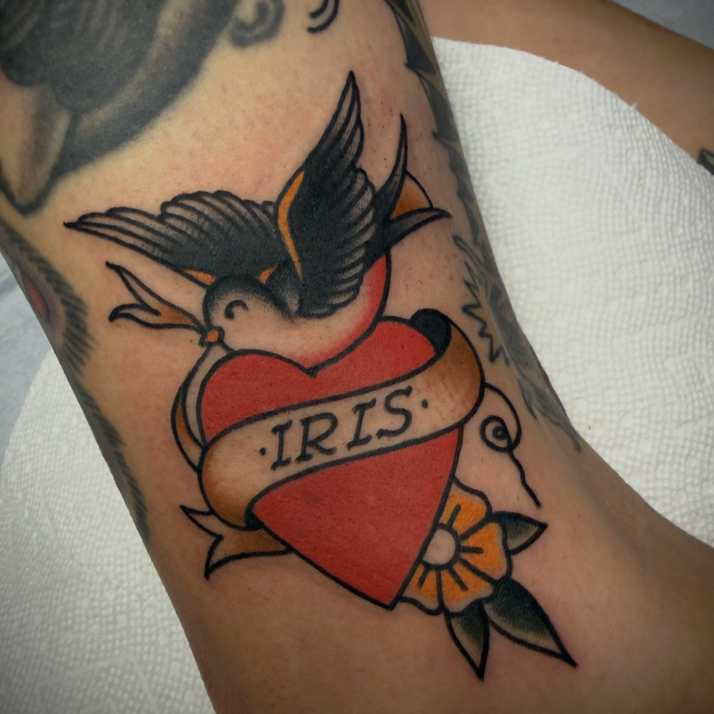 Bird and heart American traditional tattoo on the forearm by Andrew Slater