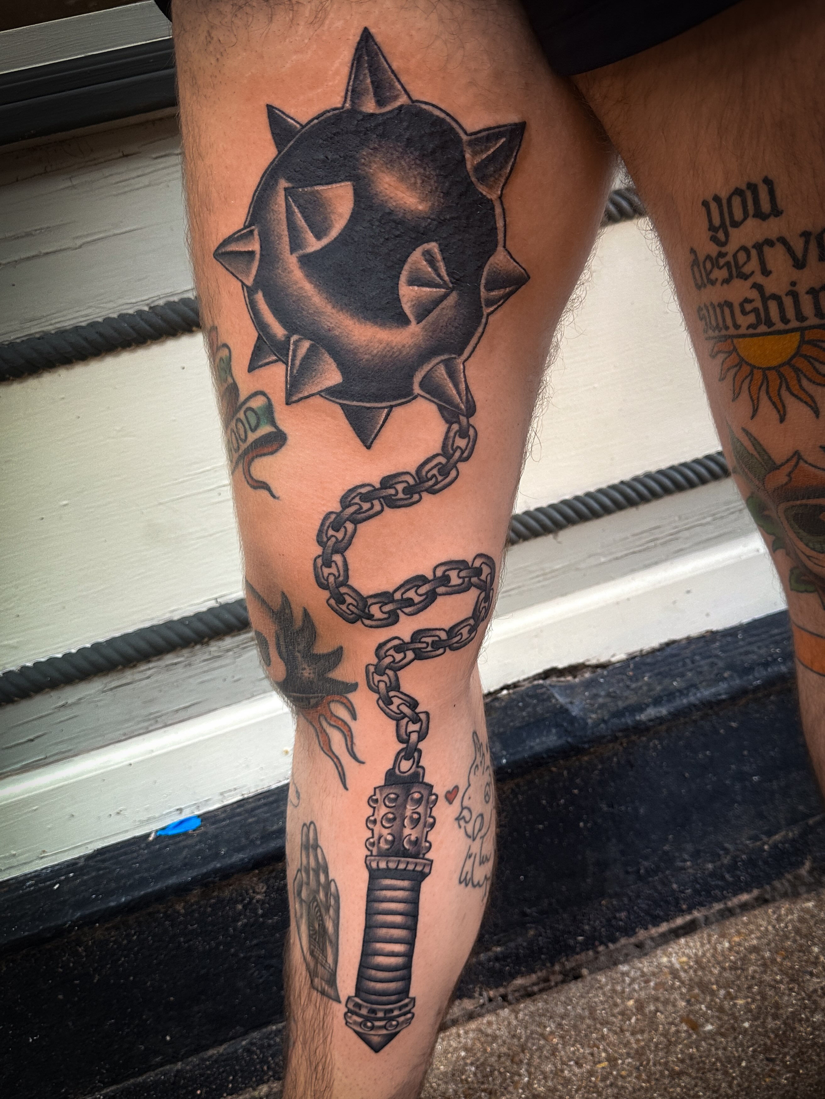 Spiked ball and chain black and grey tattoo on the leg by Stacey Colangelo