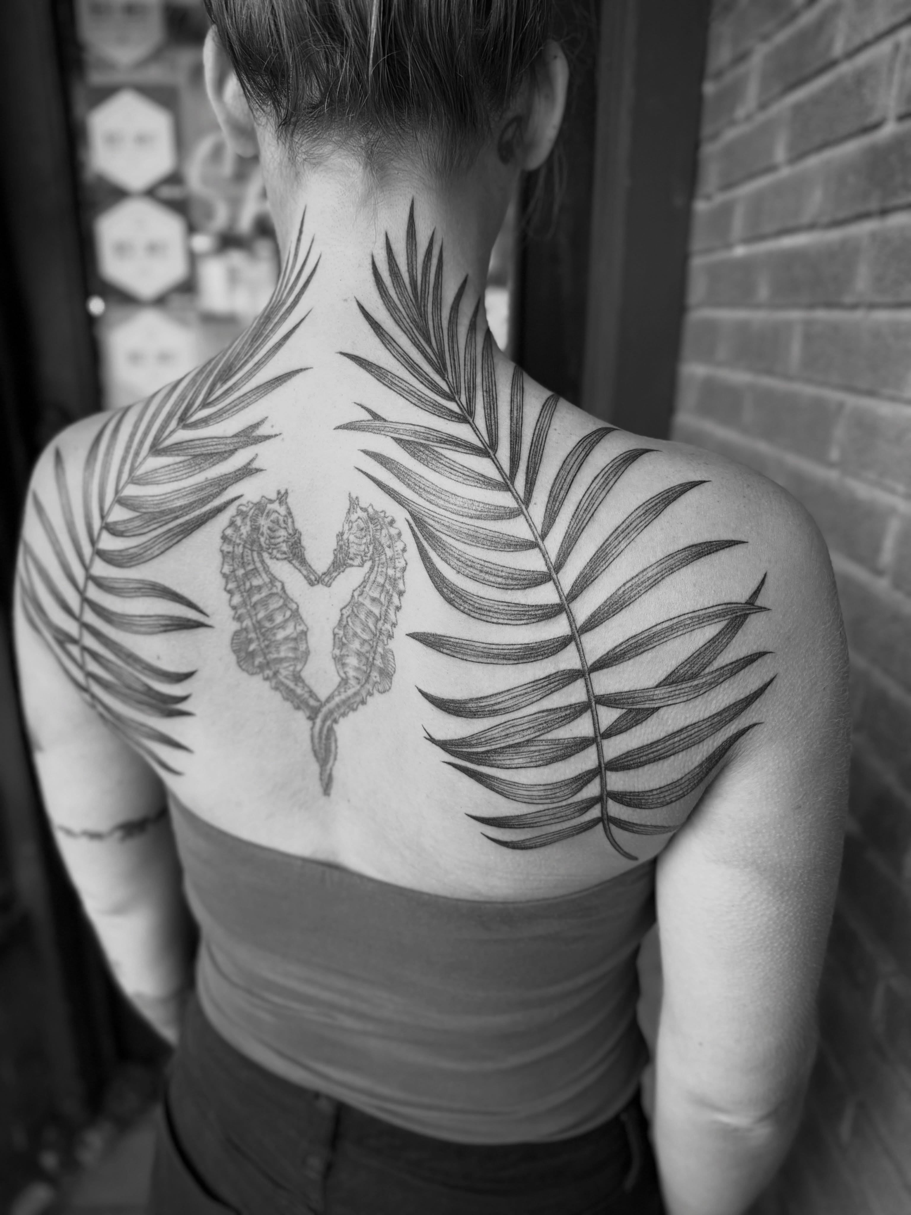 Seahorses and palm leaves realism tattoo on the back by Alex Brooke