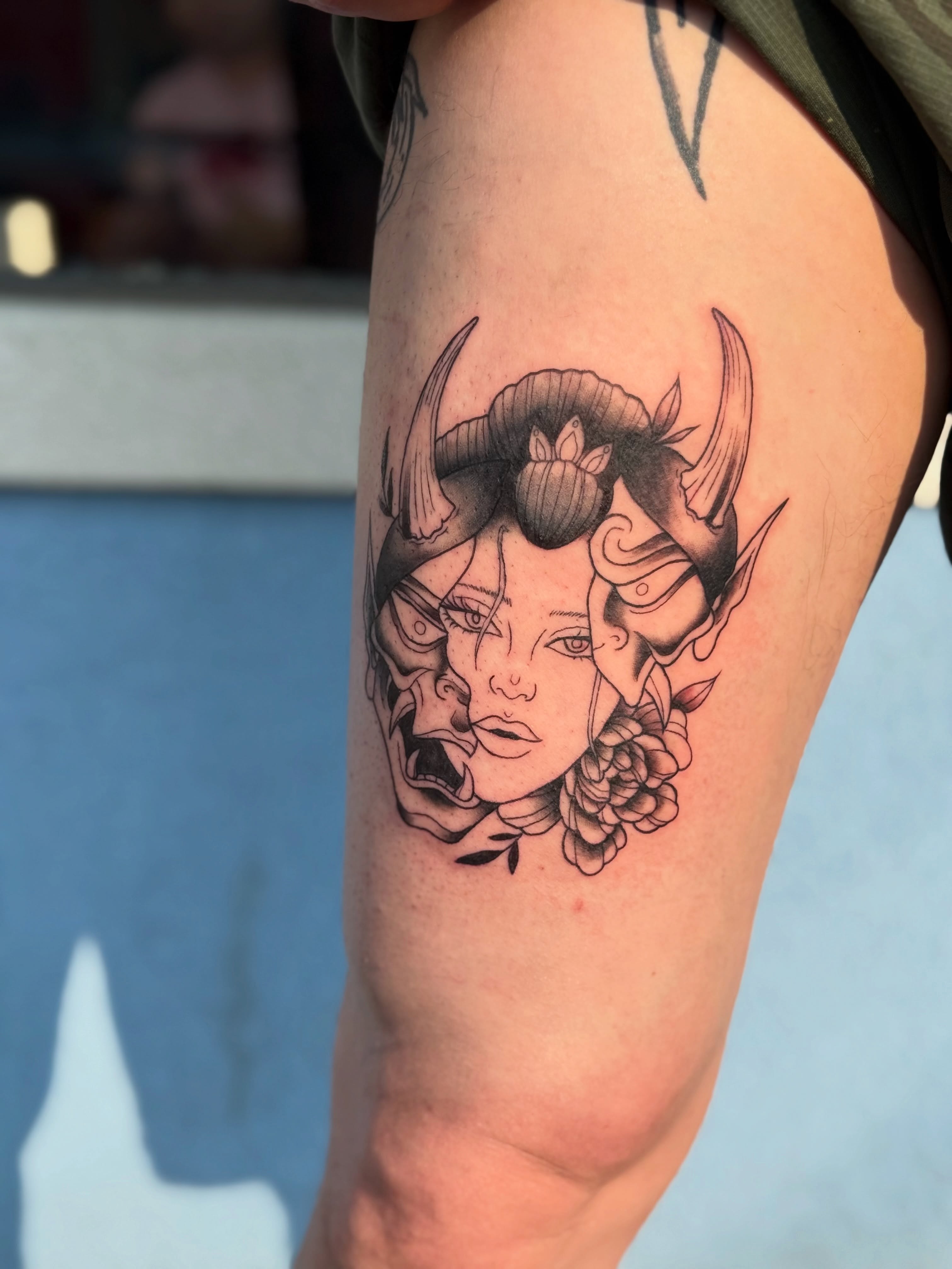 Woman's face with horns black and grey tattoo on the thigh by Harlow ❤️‍🔥
