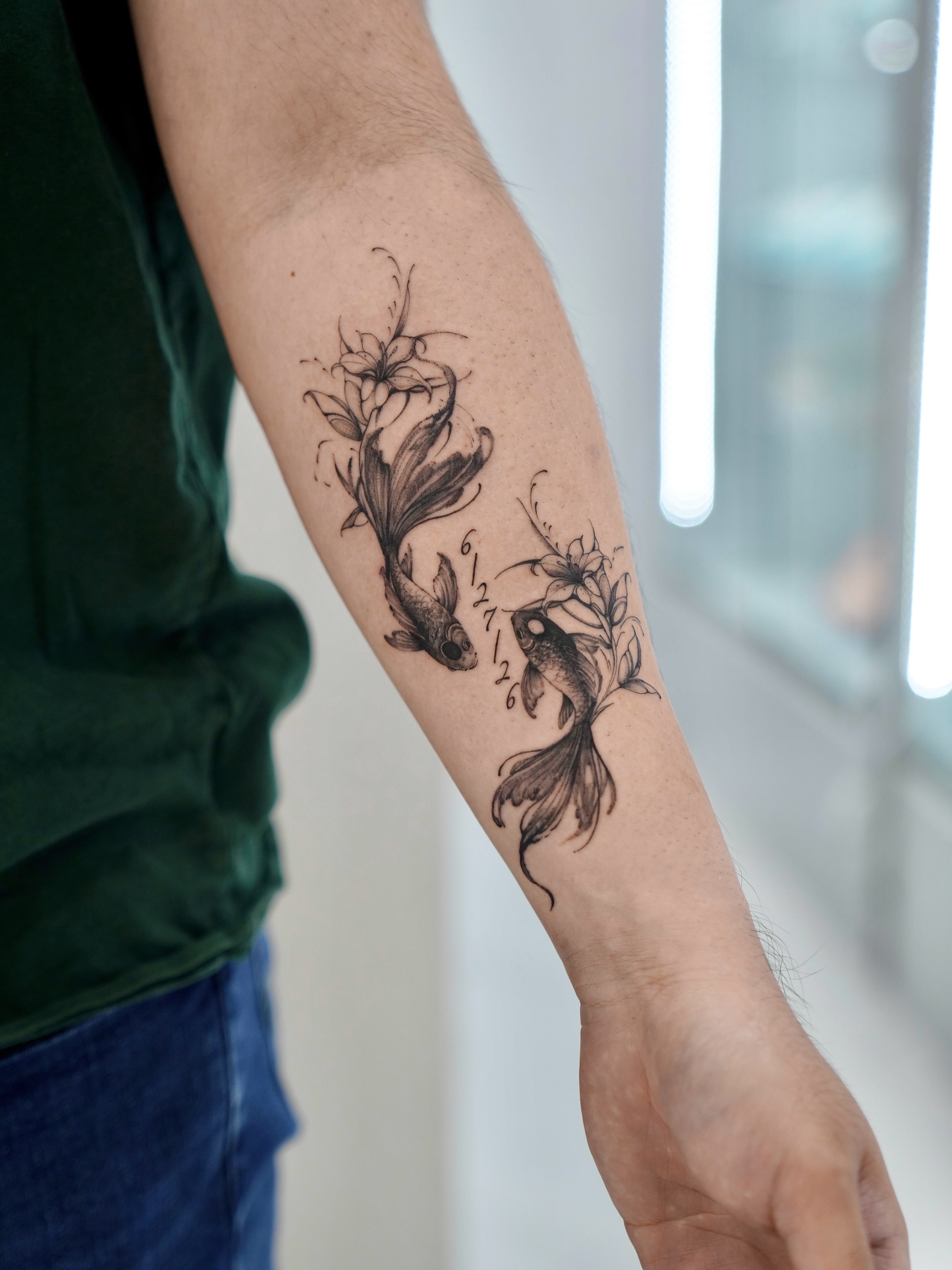 Fish and flowers black and grey tattoo on the forearm by MJ tattooist