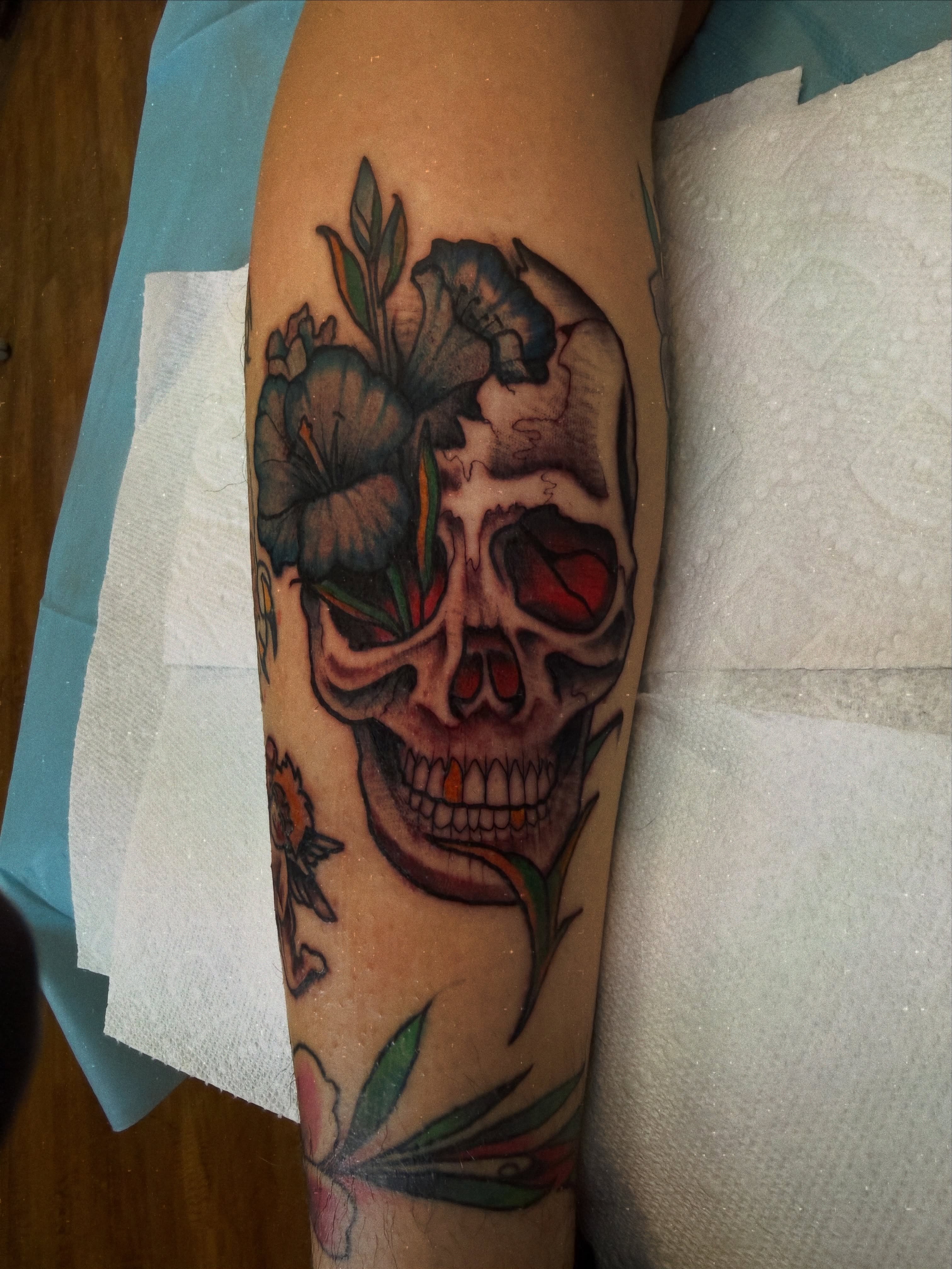 Skull with flowers realism tattoo on the forearm by Ramón Silva