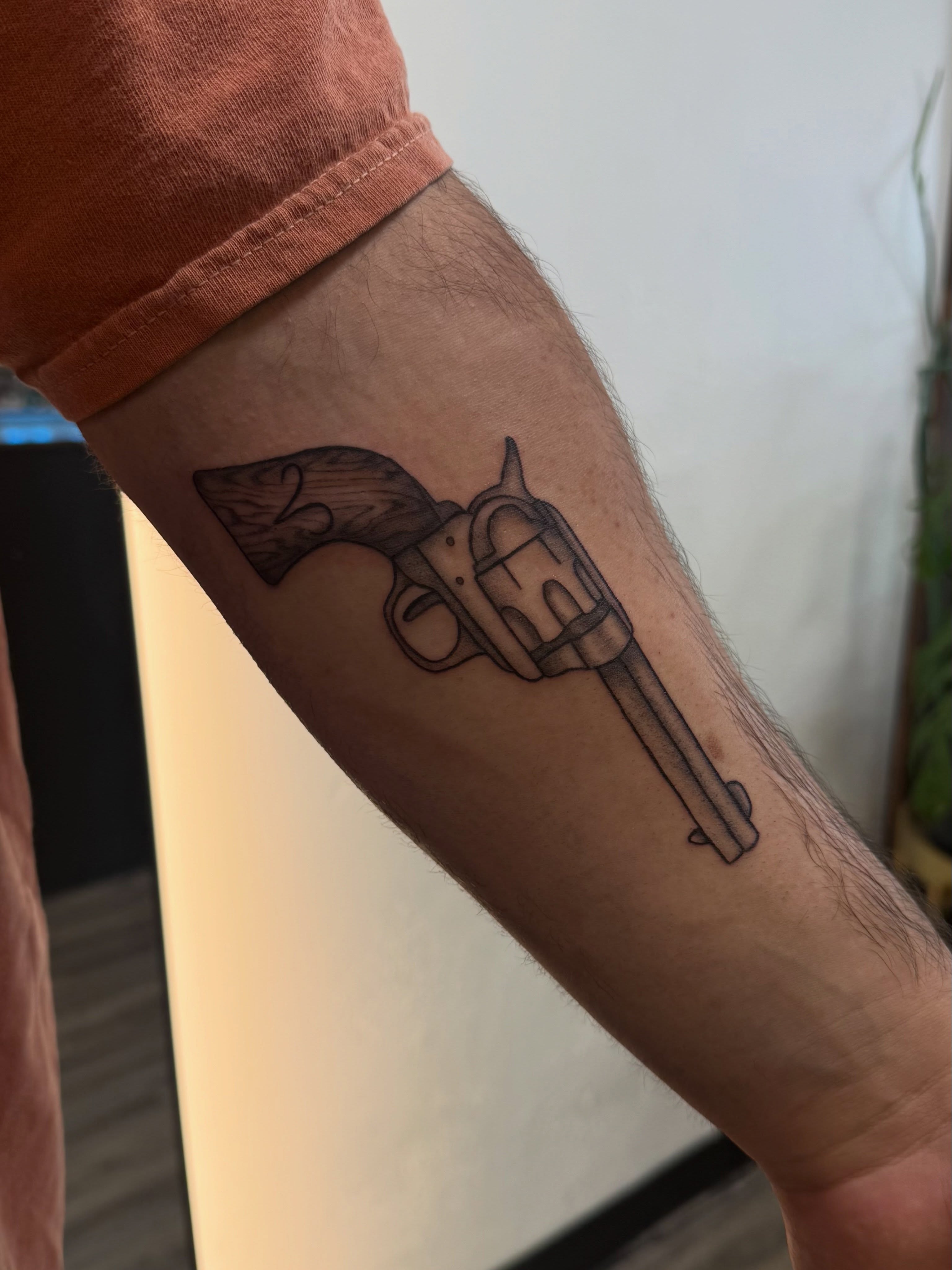 Revolver black and grey tattoo on the forearm by Kate Marie