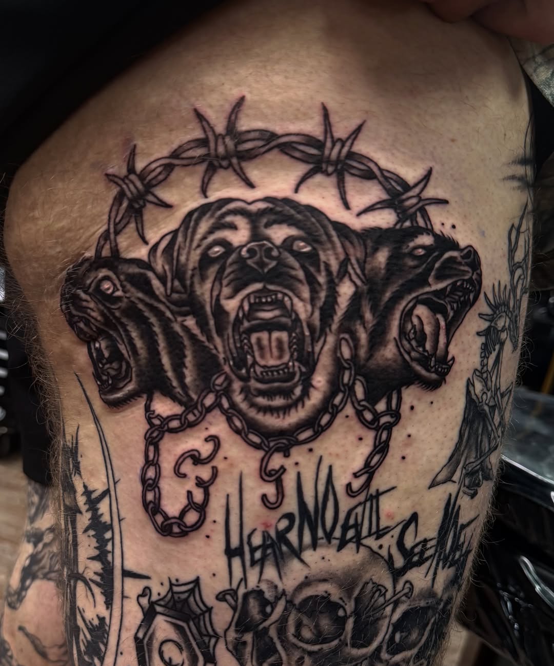 Angry dogs black and grey tattoo on the thigh by Josh Kronauer