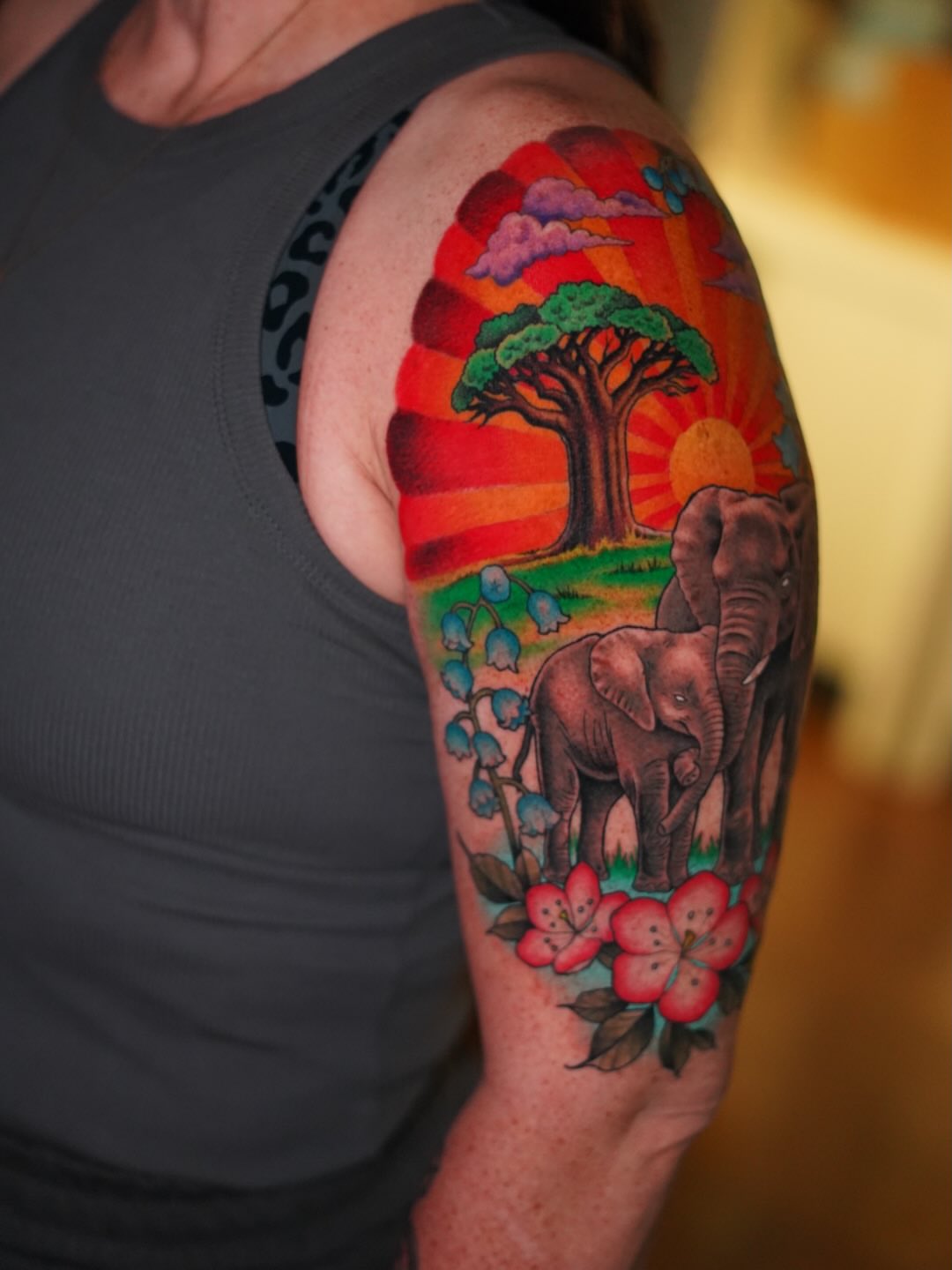 Elephants and sunset illustrative tattoo on the upper arm by Julio Ferrer