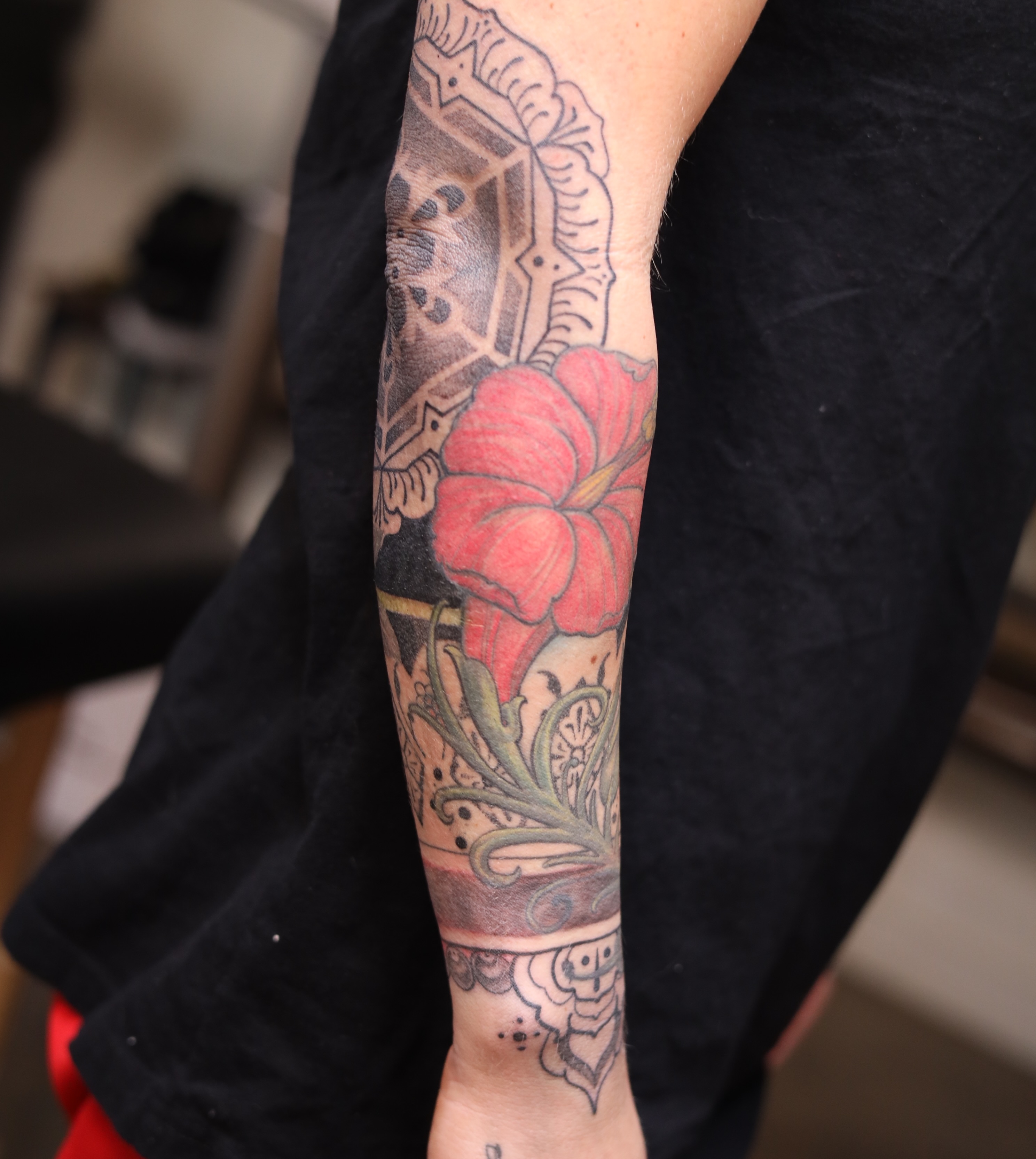 Red flower American traditional tattoo on the forearm by Caleb Ortiz