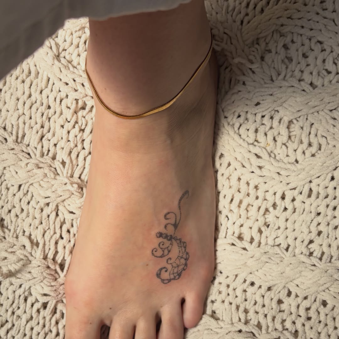 Scrollwork fine line tattoo on the foot by kari