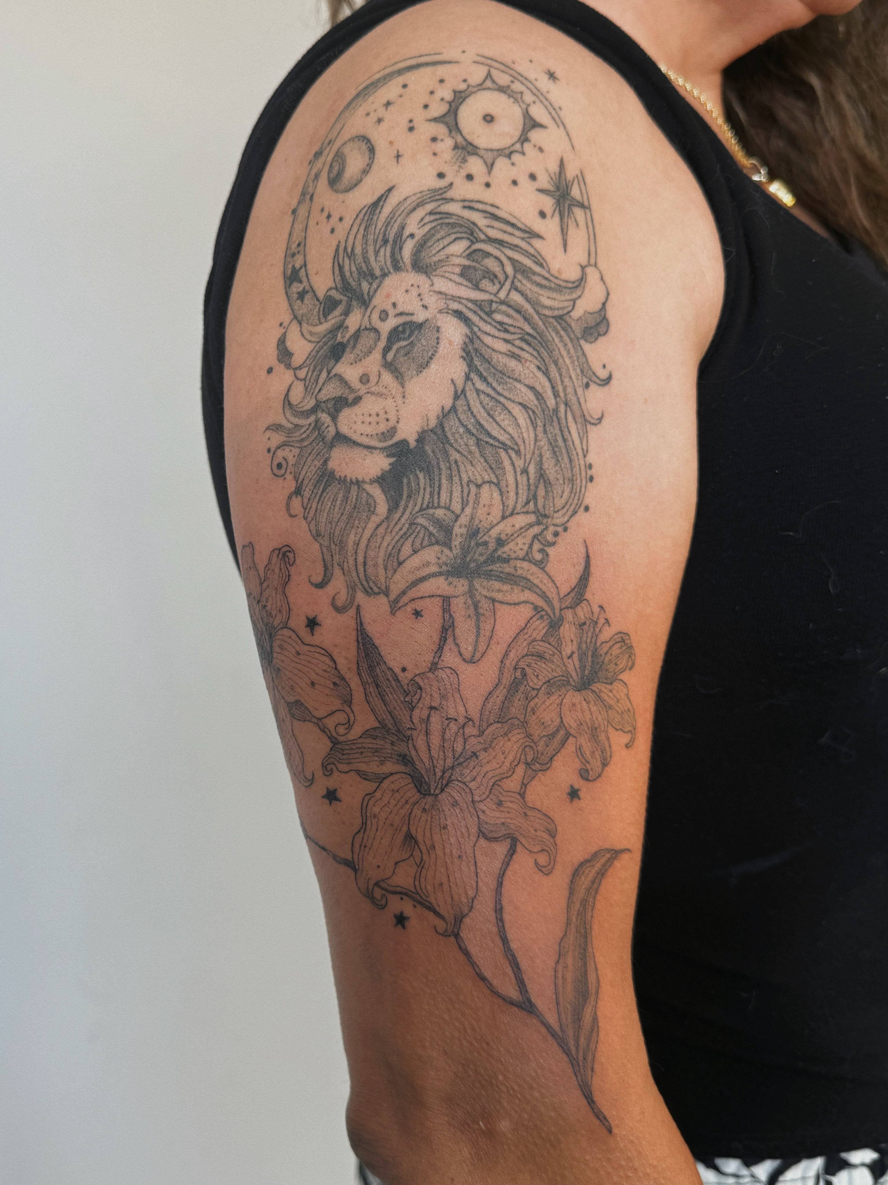 Lion and lilies realism tattoo on the shoulder by Paulina Vazquez
