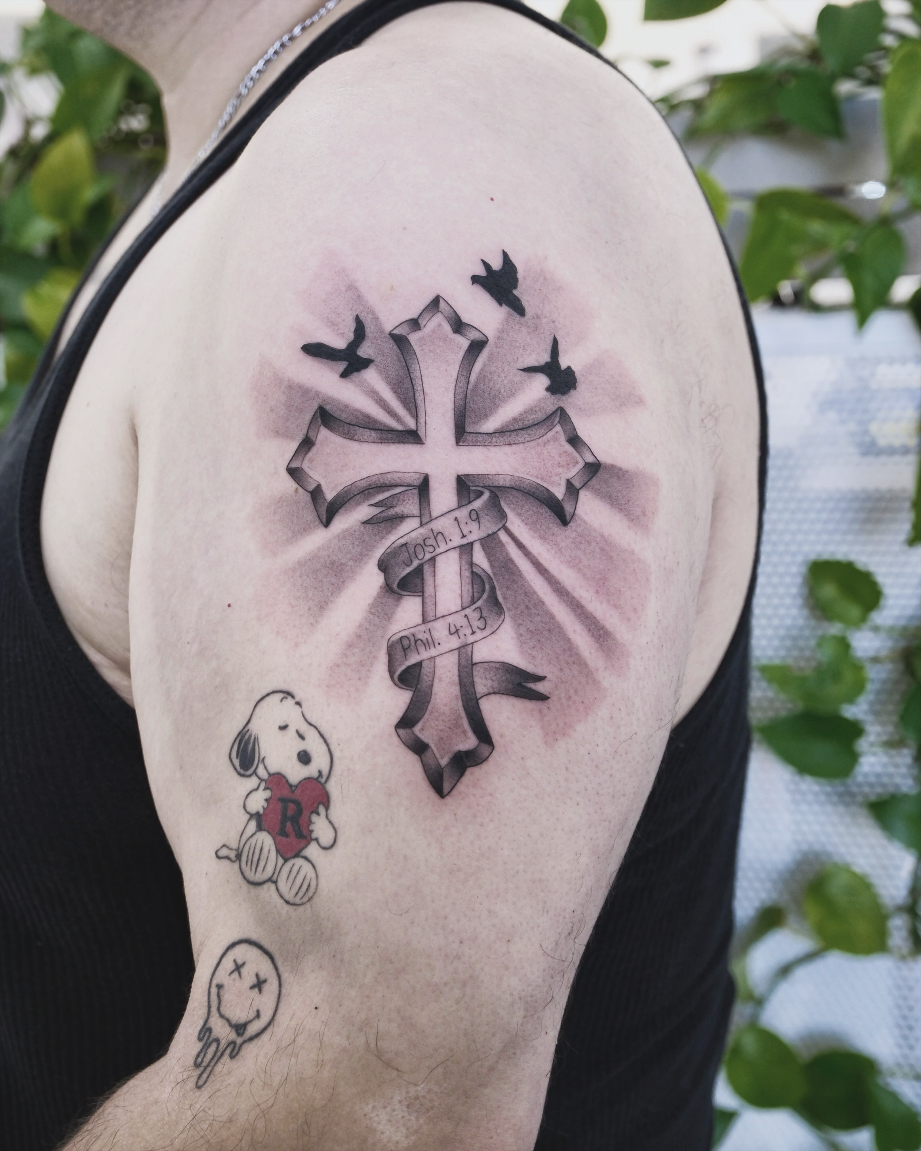 Cross with ribbon black and grey tattoo on the shoulder by Raytattooist