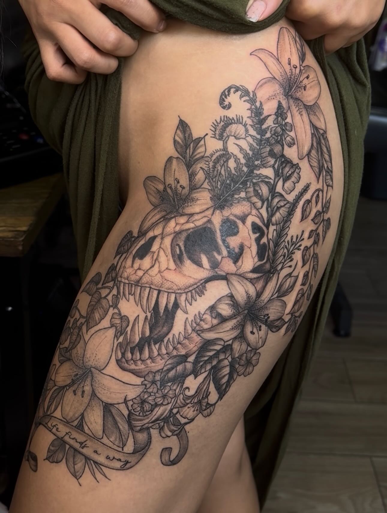 Dinosaur skull with flowers realism tattoo on the thigh by Mickey