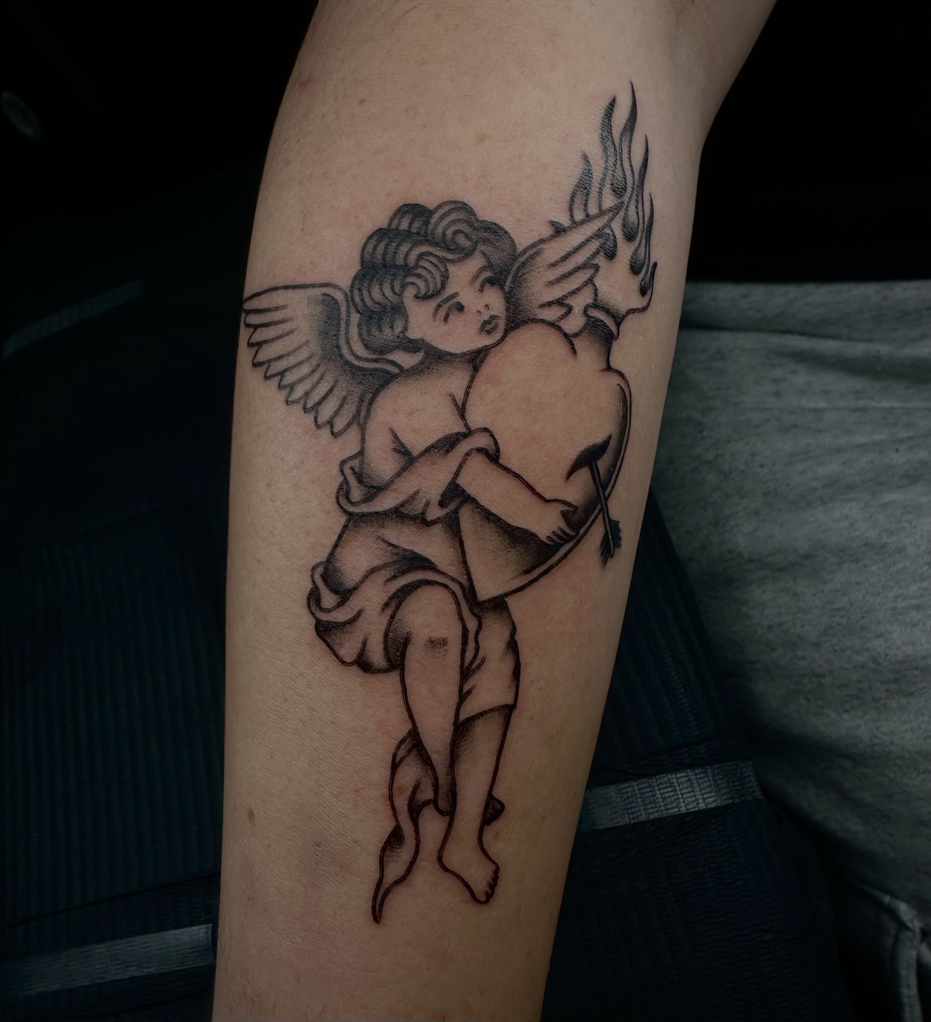 Cherub couple black and grey tattoo on the forearm by emma christine