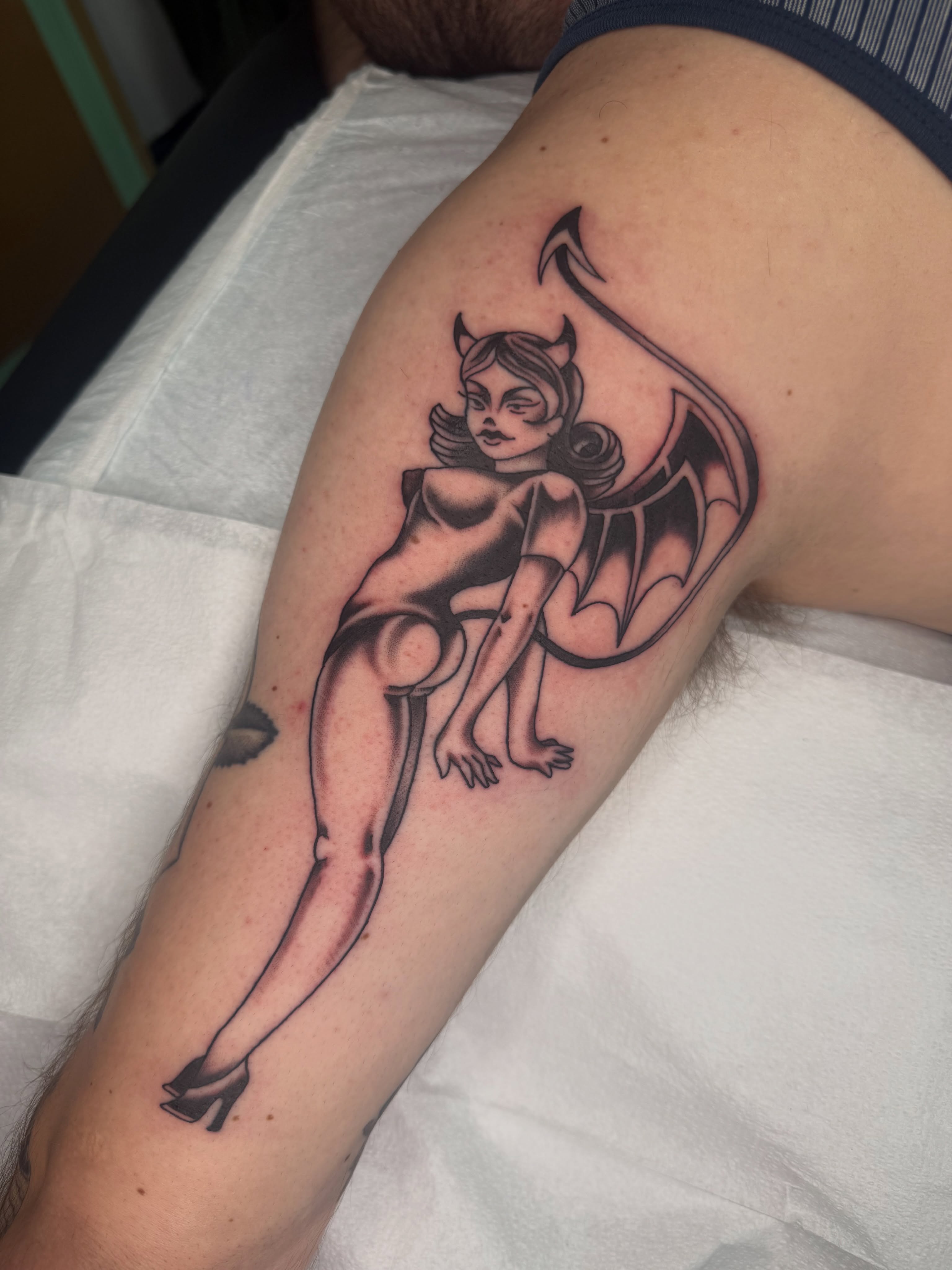 Devil pin-up girl black and grey tattoo on the forearm by Joe Weber, Monona, Wisconsin
