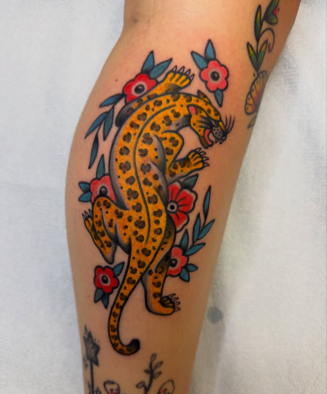 Leopard and flowers American traditional tattoo on the forearm by Hannah Jean