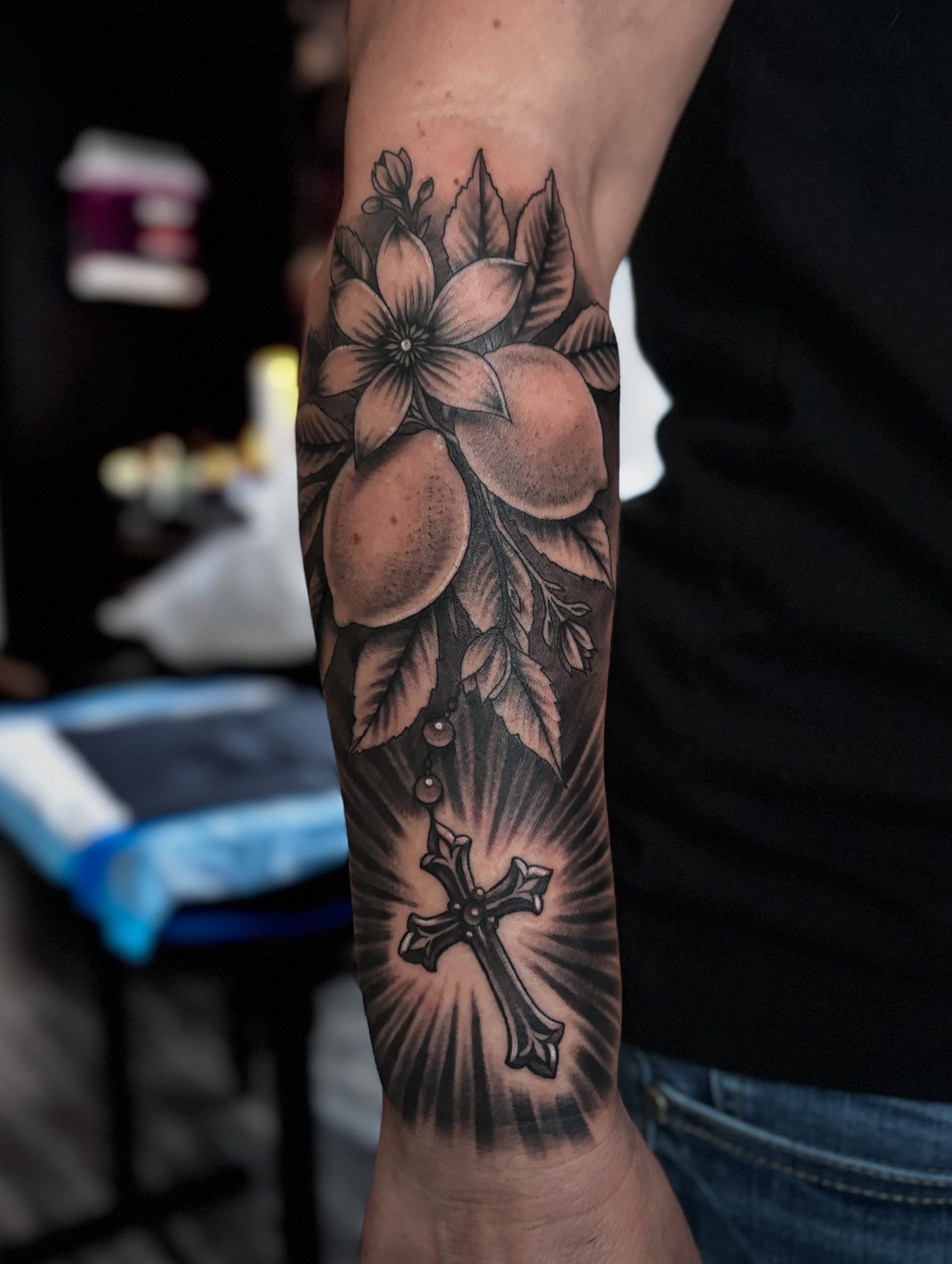 Cross and flowers black and grey tattoo on the forearm by Luis Marrufo
