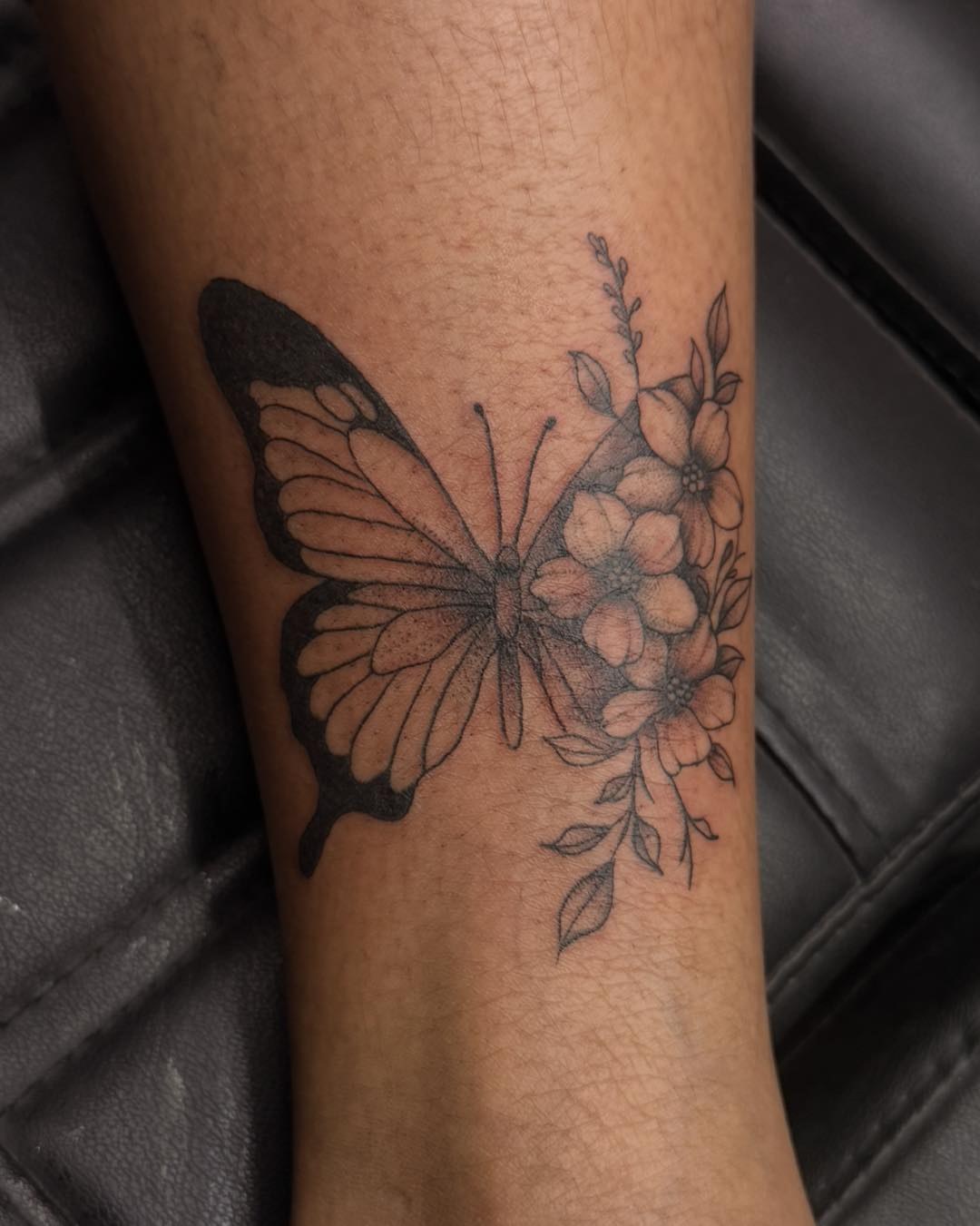 Butterfly and flowers black and grey tattoo on the forearm by Flamboyant