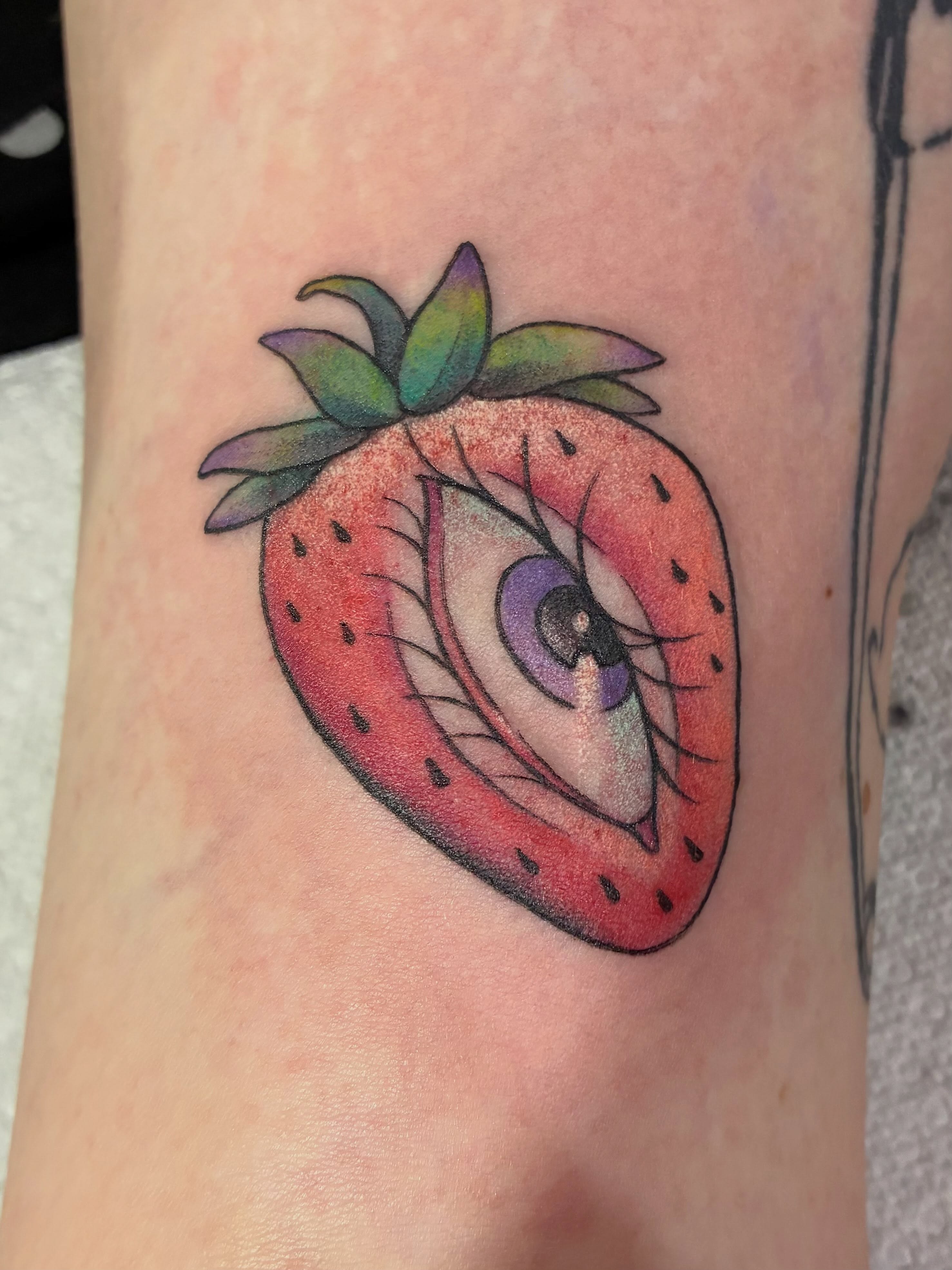 Strawberry with eye realism tattoo on the forearm by Natalie Spuhler