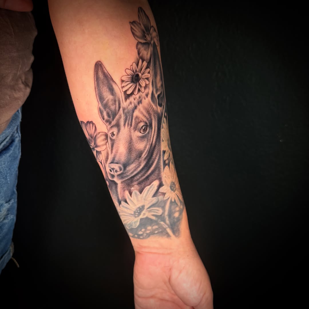 Dog with flowers realism tattoo on the forearm by Monica Gonzalez