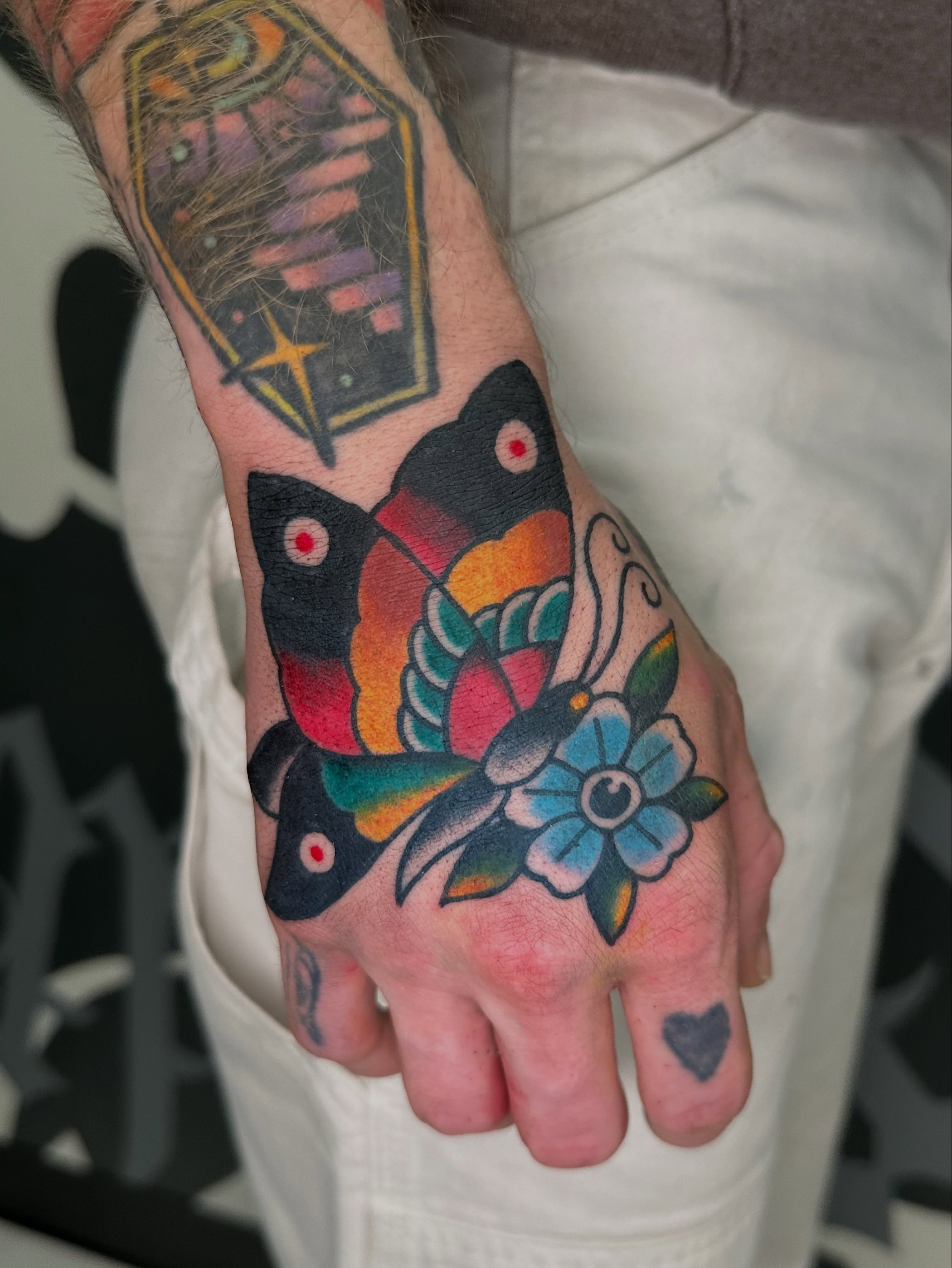 Butterfly and flower American traditional tattoo on the hand by Andy Sharik
