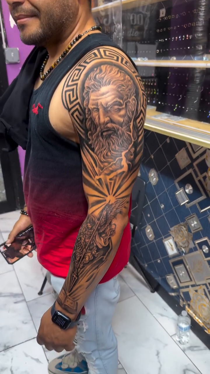 Bust of Zeus with sun rays realism tattoo on the upper arm by Jose Onasis Disla, New York, New York