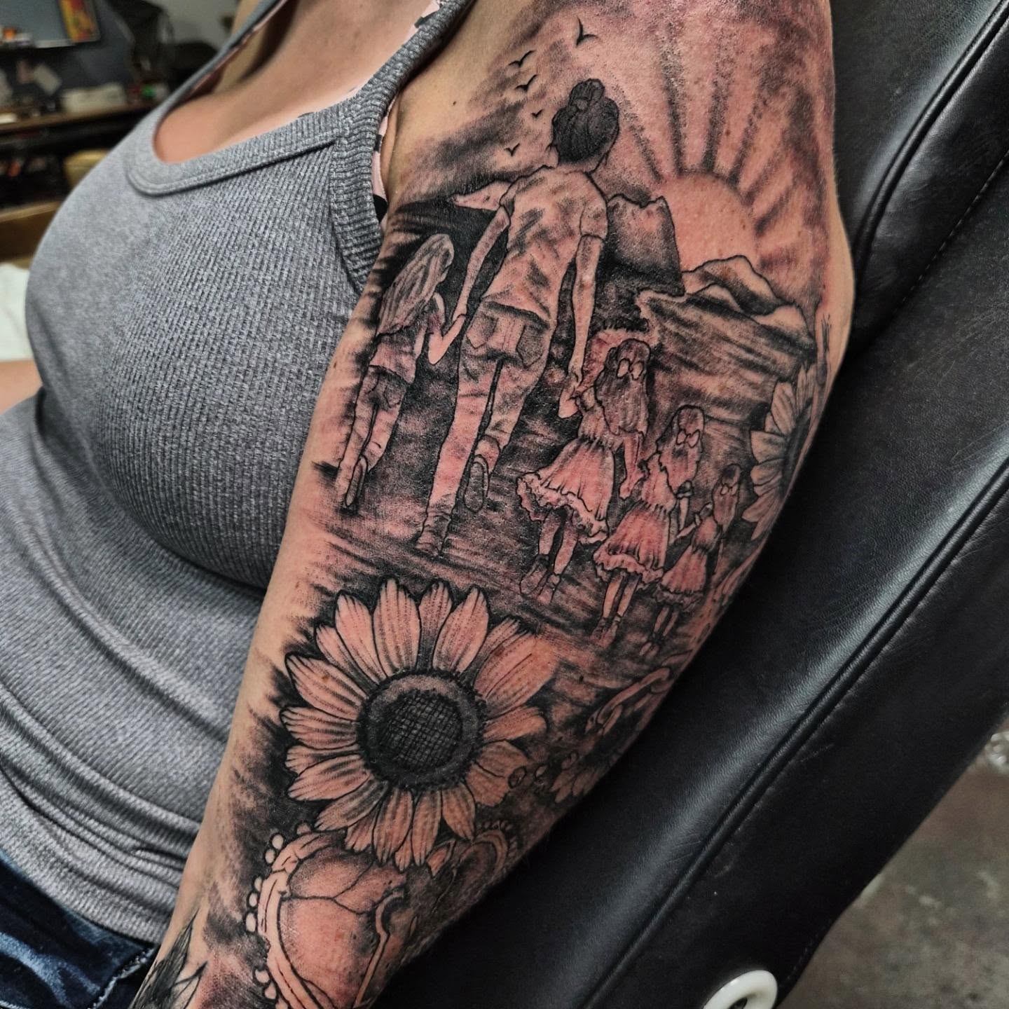 Family scene with sunflower realism tattoo on the forearm by Taylor Popkins