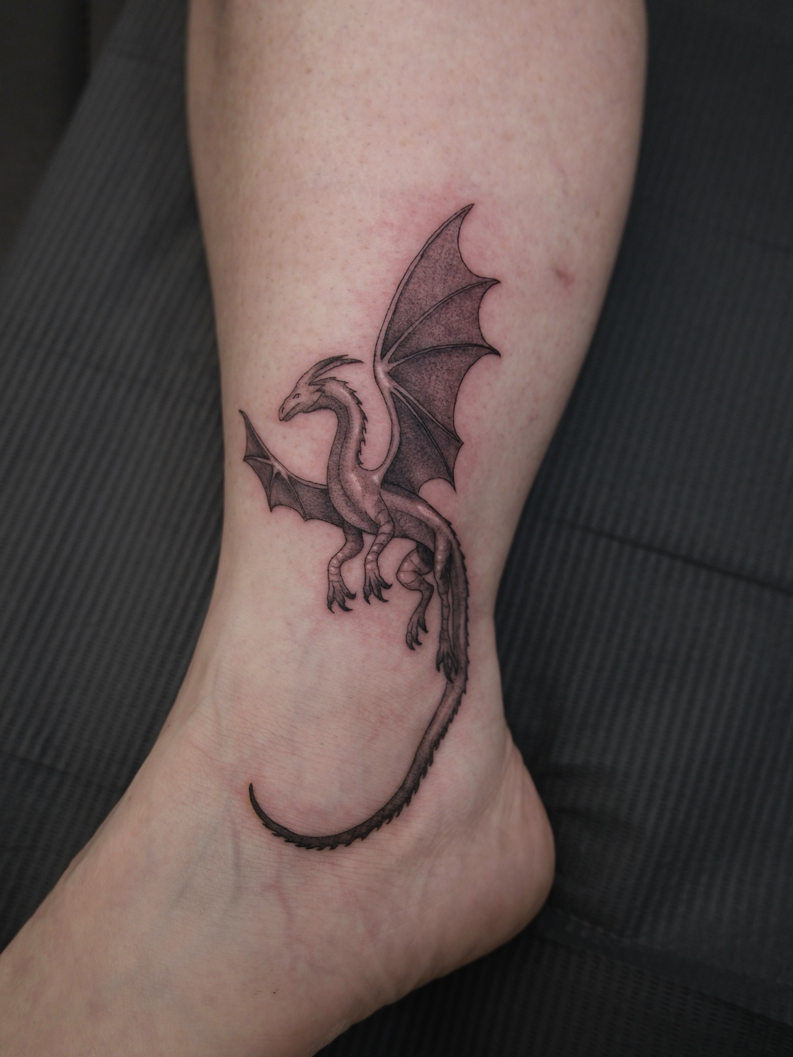 Dragon black and grey tattoo on the foot by Kiana Hope