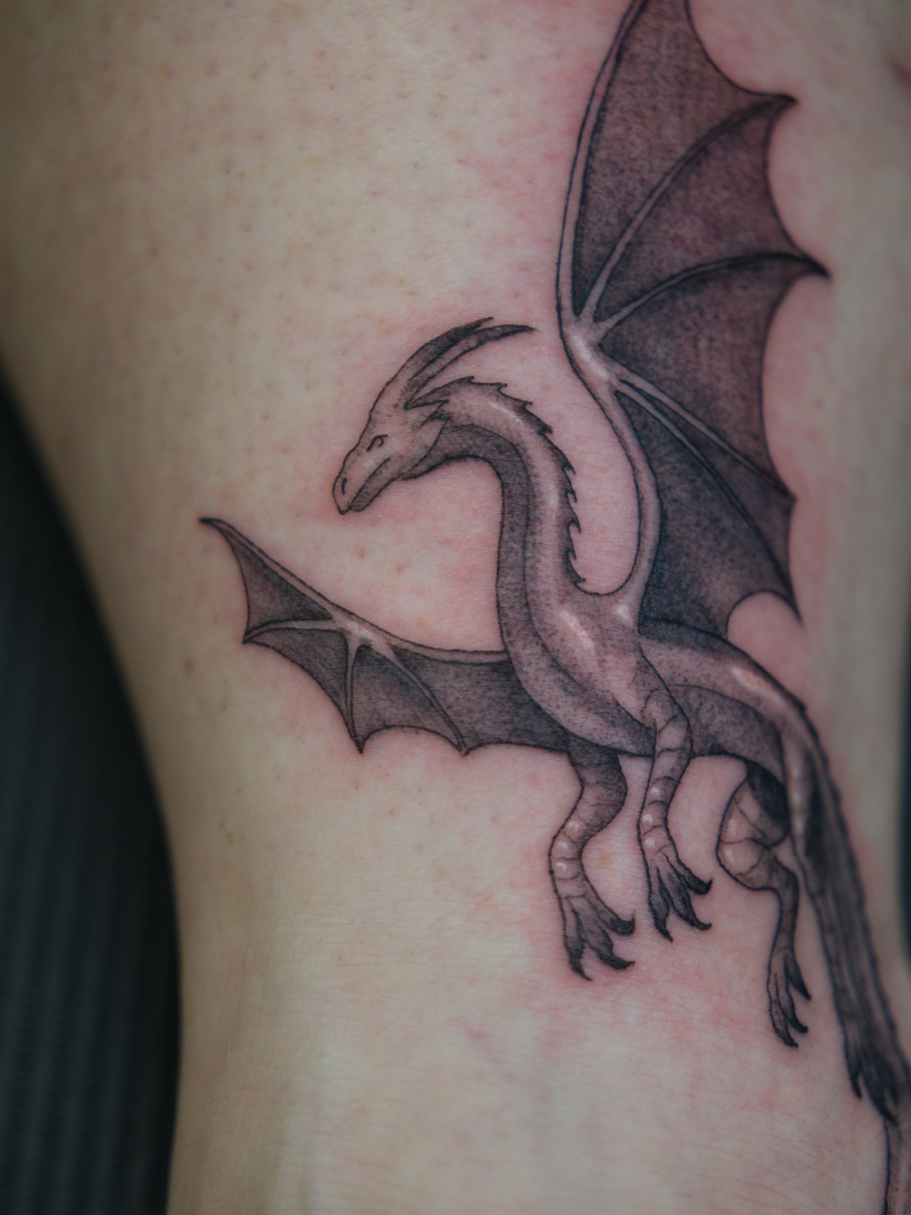 Dragon black and grey tattoo on the thigh by Kiana Hope