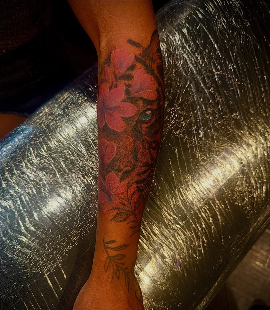 Tiger with flowers realism tattoo on the forearm by Clifford Jordan