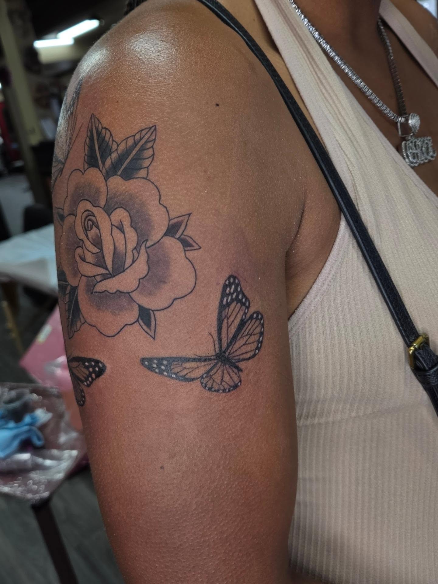 Rose and butterfly black and grey tattoo on the upper arm by Jessica Duggan