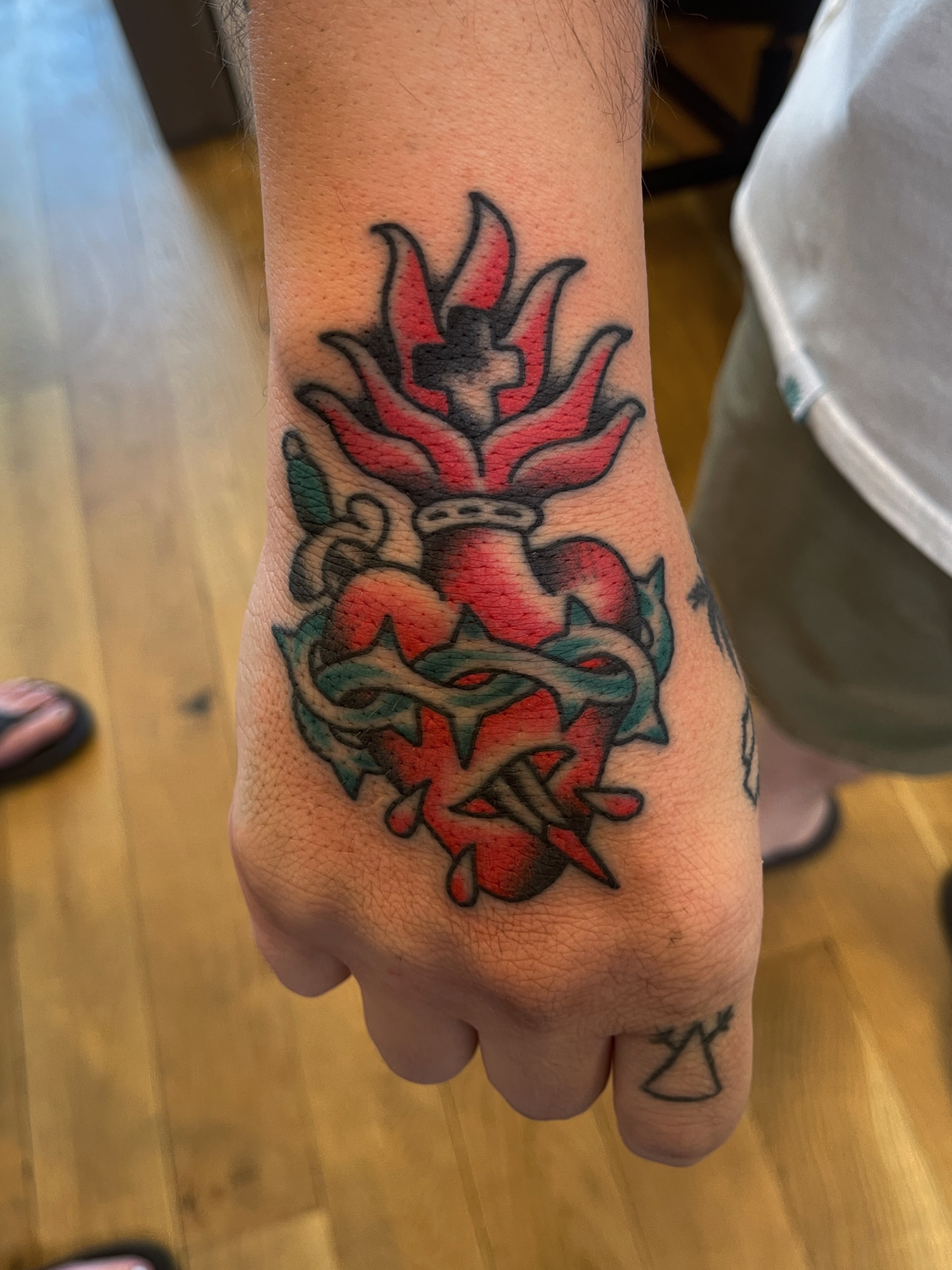 Heart with cross American traditional tattoo on the hand by Spencer Reisbeck