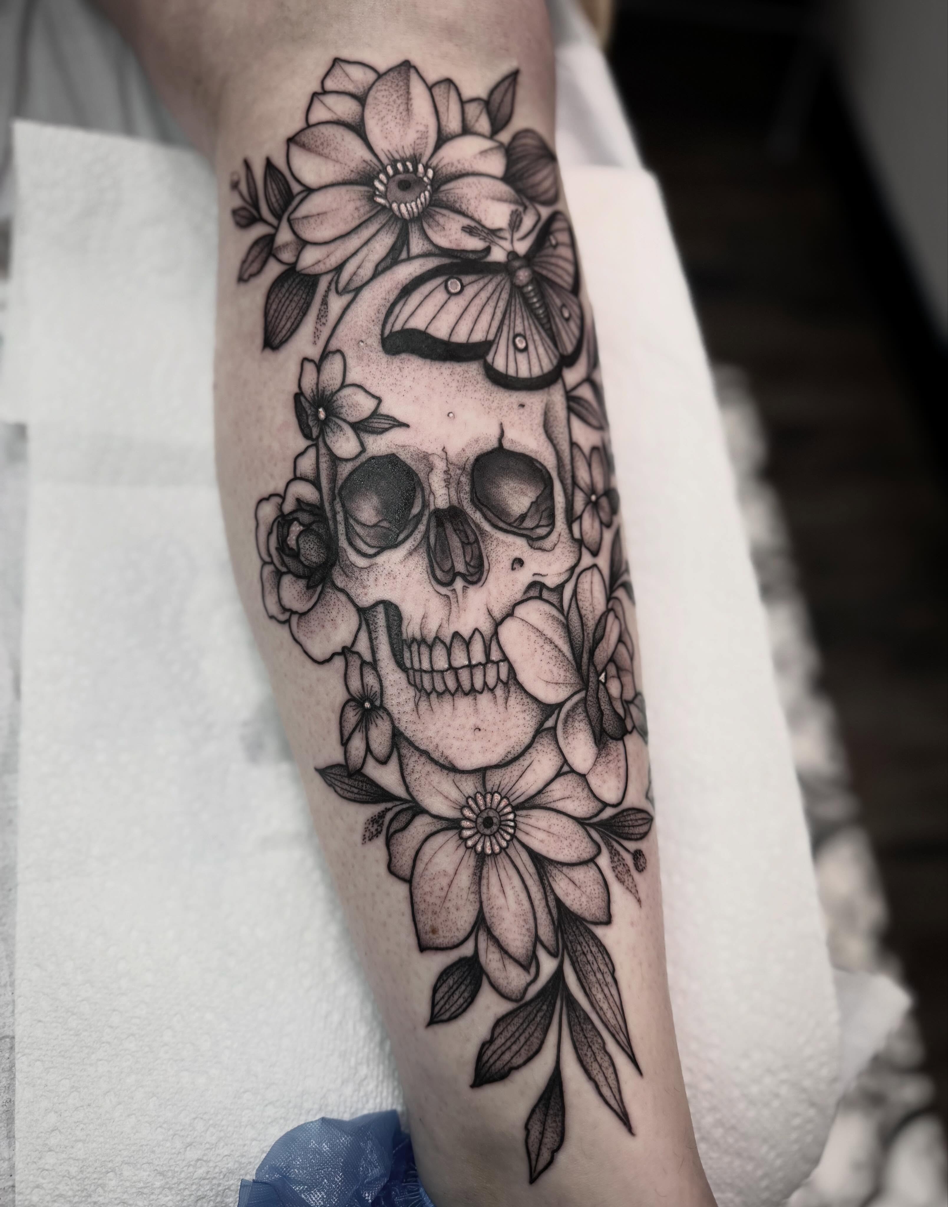 Skull with flowers realism tattoo on the forearm by Ashleigh Lapole