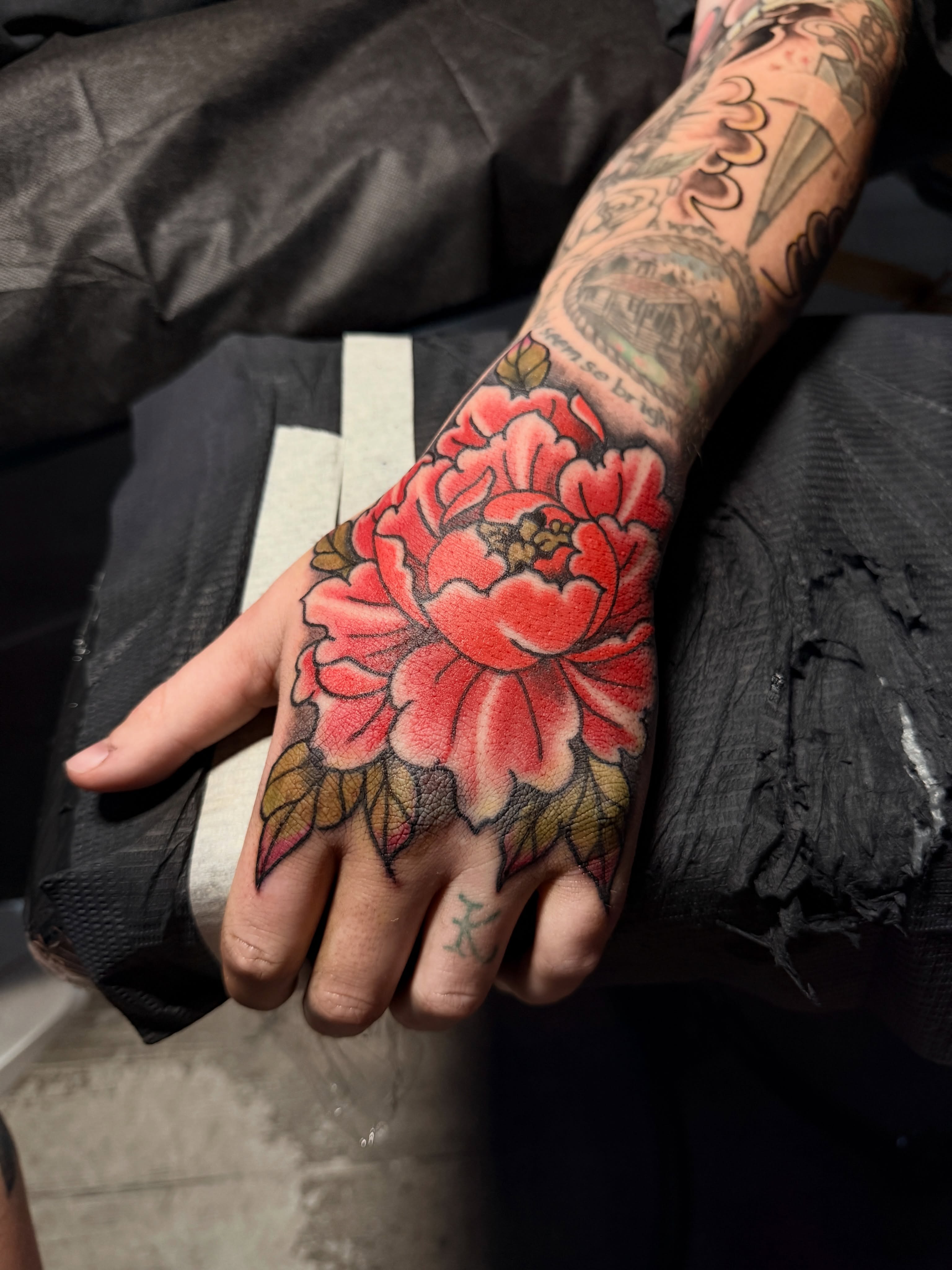 Peony American traditional tattoo on the hand by Noah Morris