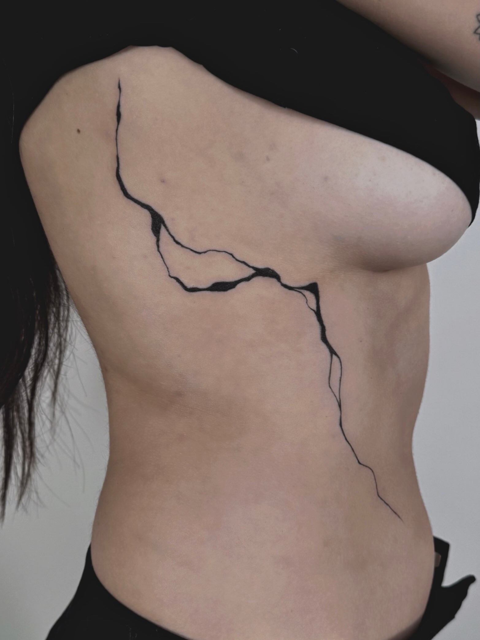 Crack minimalist tattoo on the torso by Kaelyn