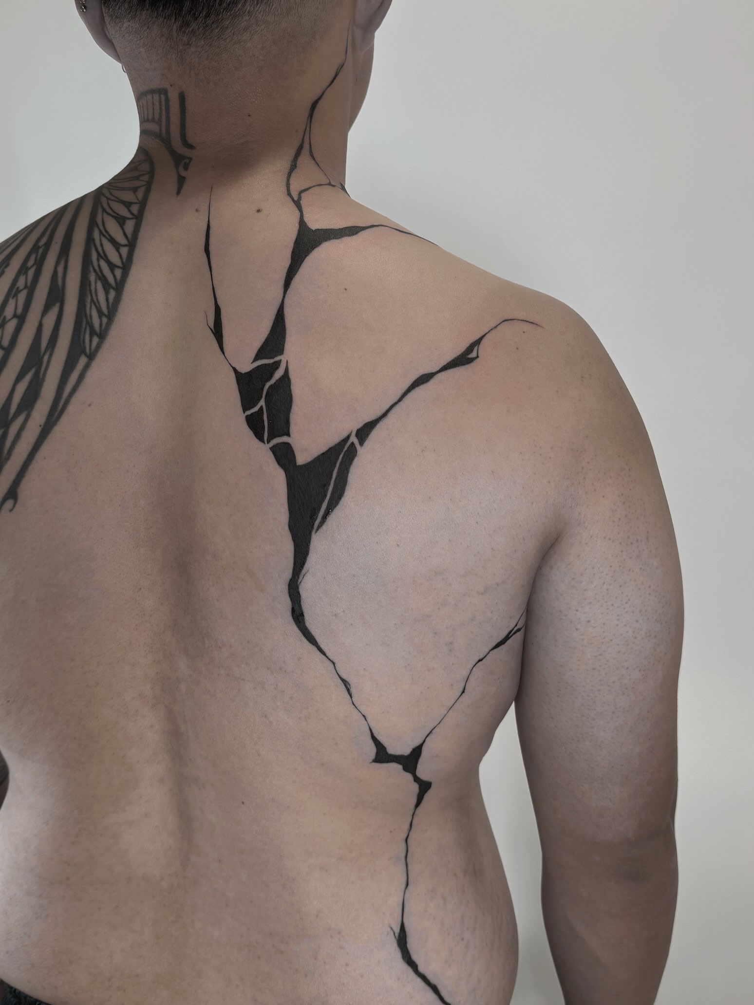 Cracked surface geometric tattoo on the back by Kaelyn
