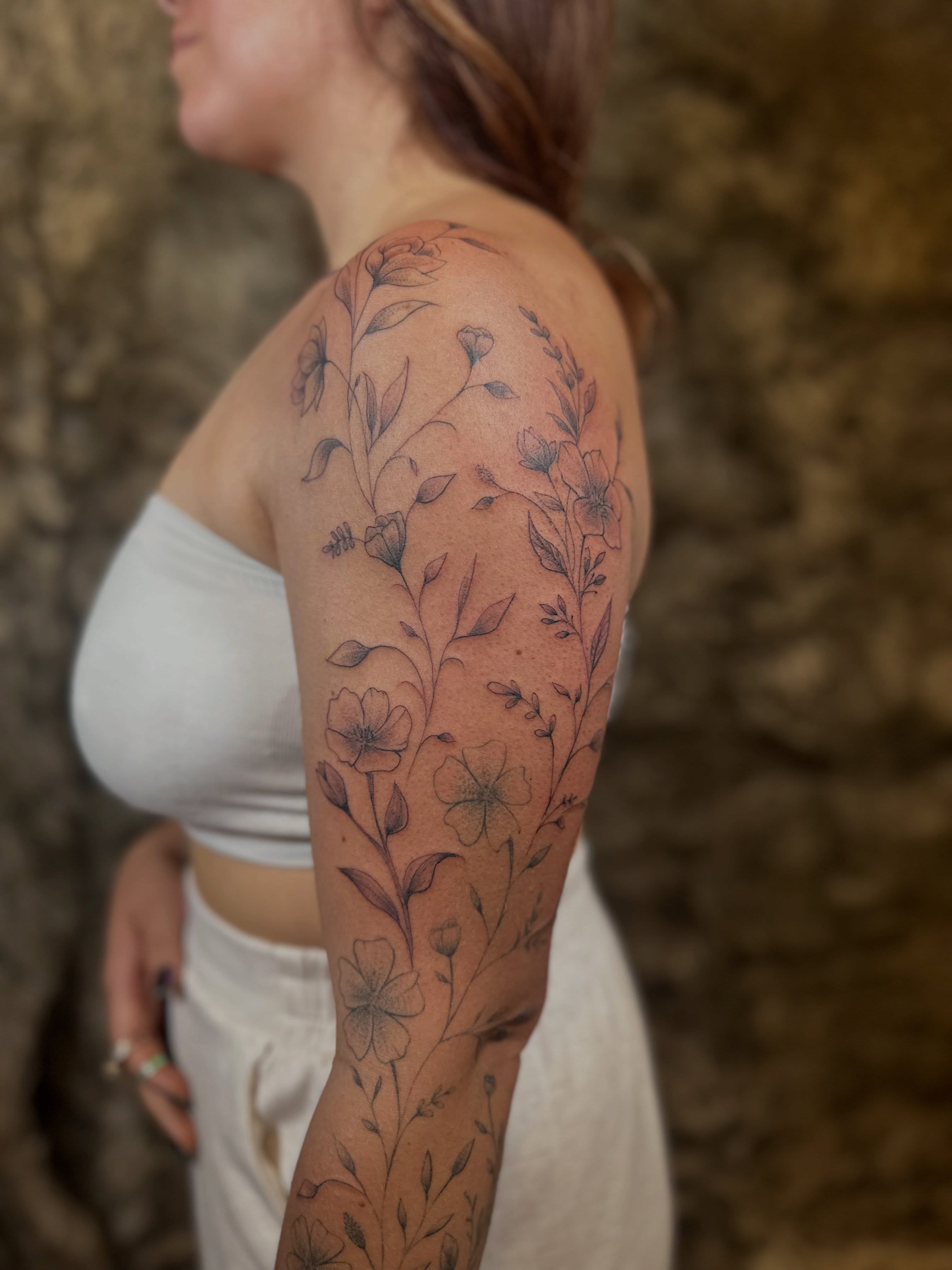 Floral arrangement black and grey tattoo on the upper arm by Ric Castellon Tattoo Artist, Los Angeles, California
