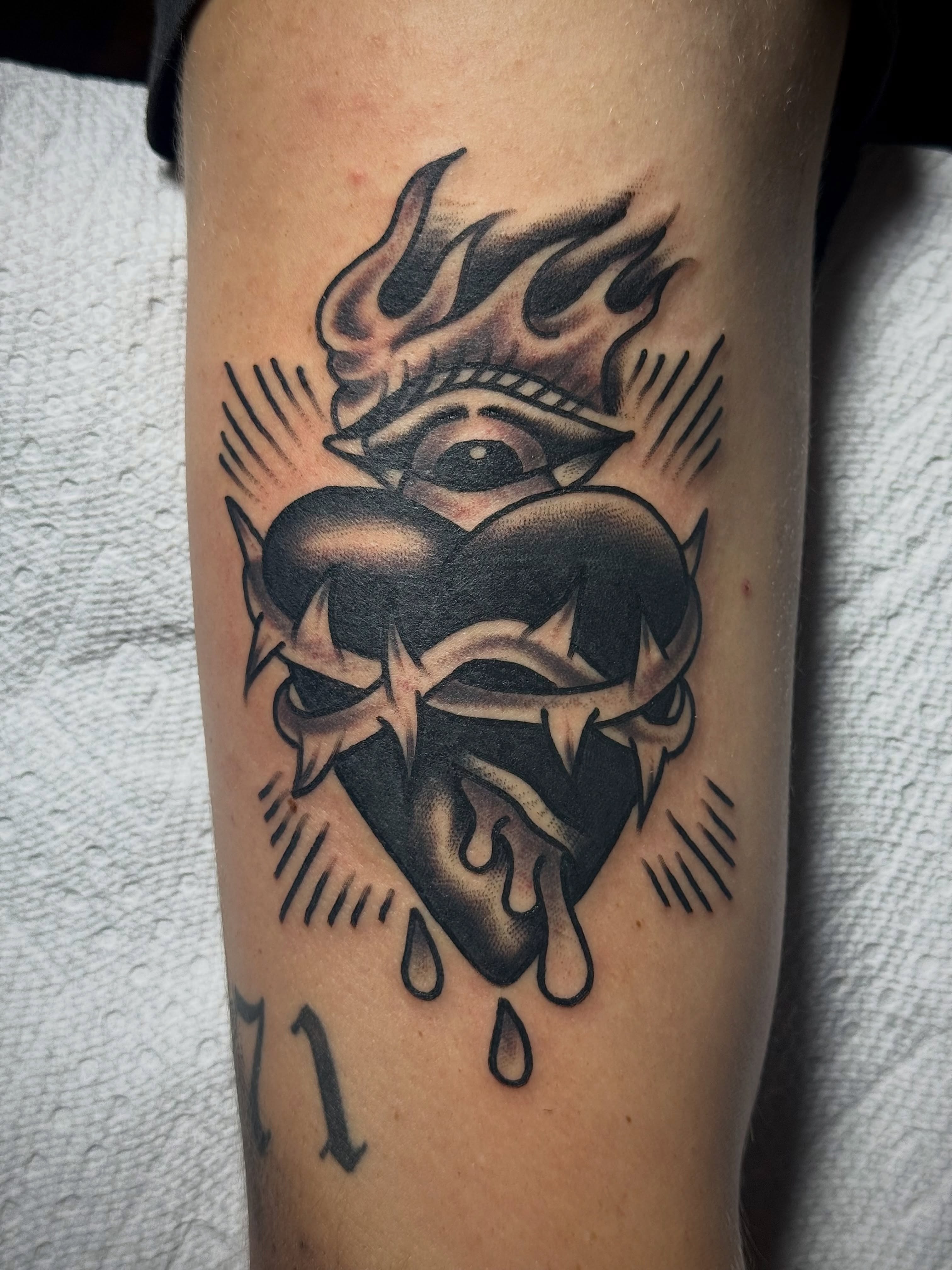 Heart with flames and eye American traditional tattoo on the forearm by Chuck Derek Whitaker