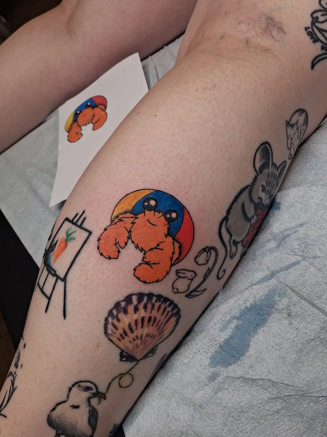 Crab and beach ball new school tattoo on the forearm by Amber Tattoos