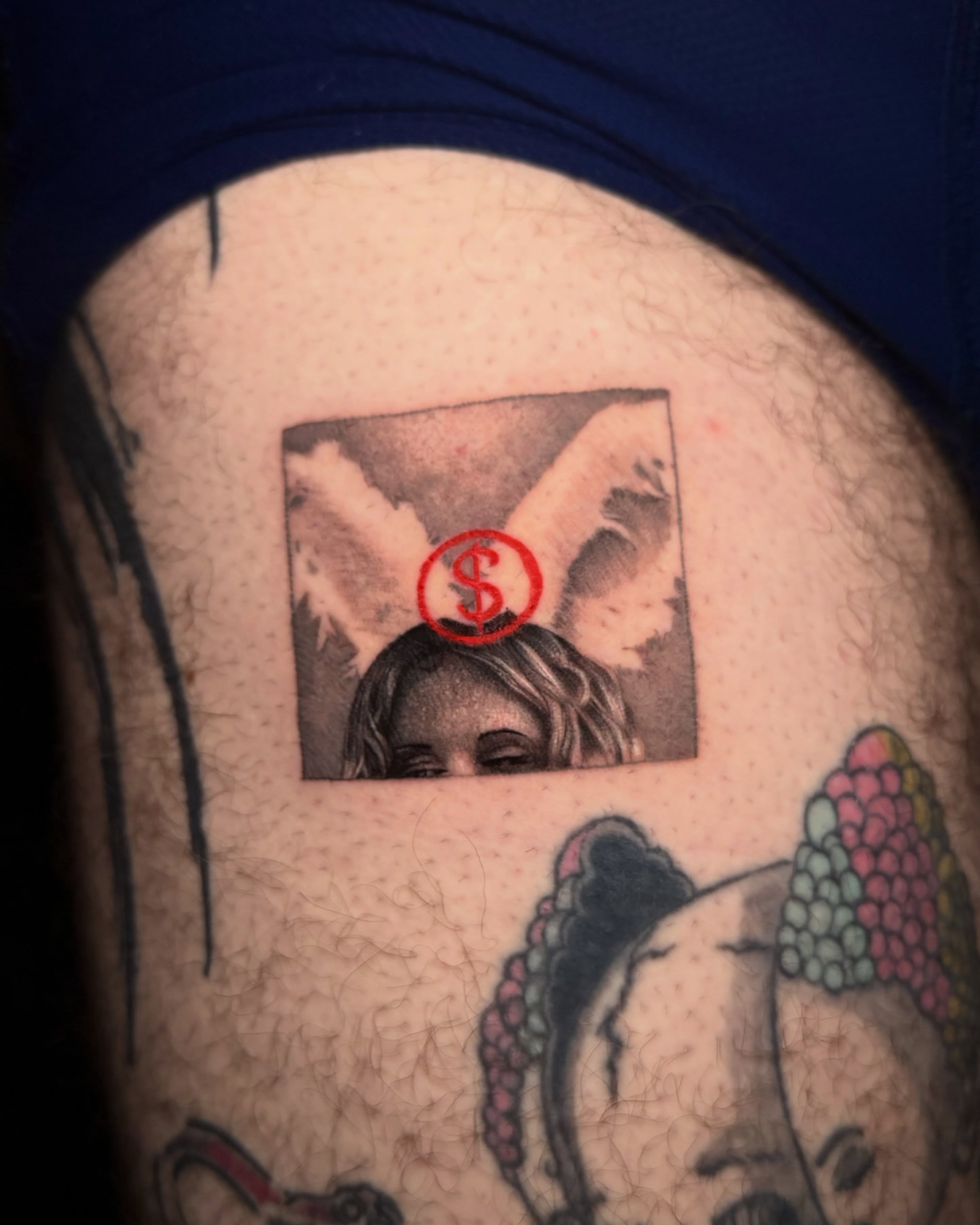 Doll with dollar sign realism tattoo on the thigh by Giovanni Rodriguez, Eastpointe, Michigan