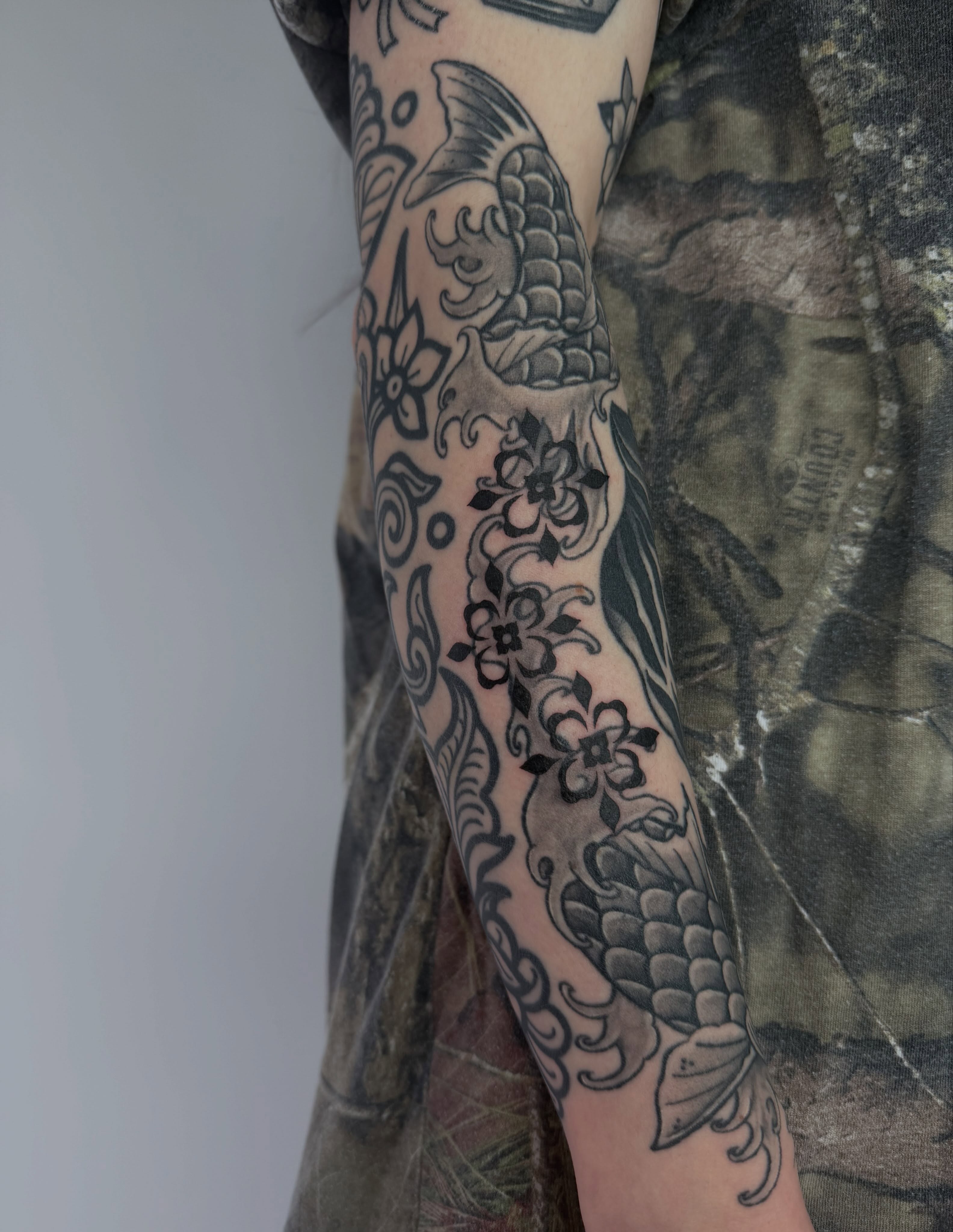 Koi fish and floral patterns American traditional tattoo on the forearm by Leah Ramos