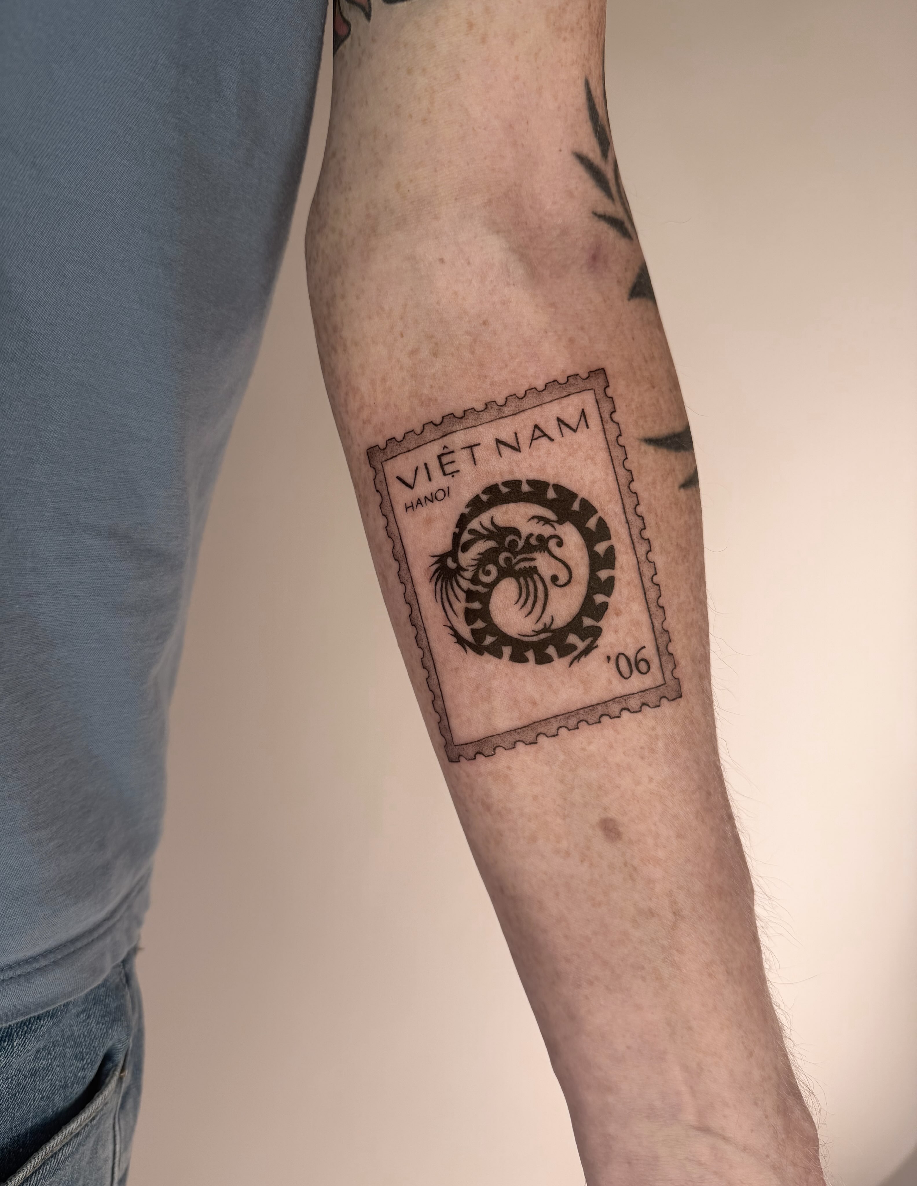 Stamp black and grey tattoo on the forearm by Leah Ramos