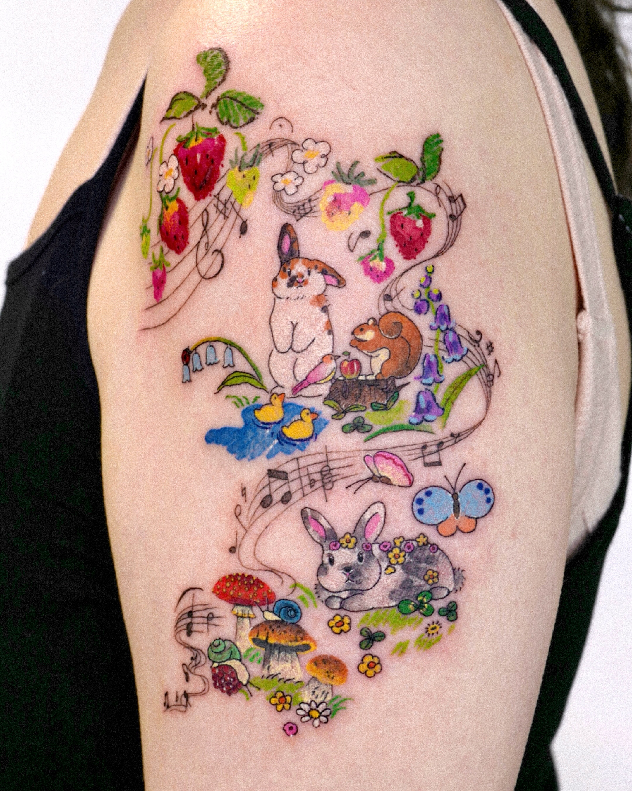 Bunny and strawberries watercolor tattoo on the upper arm by dahye lee